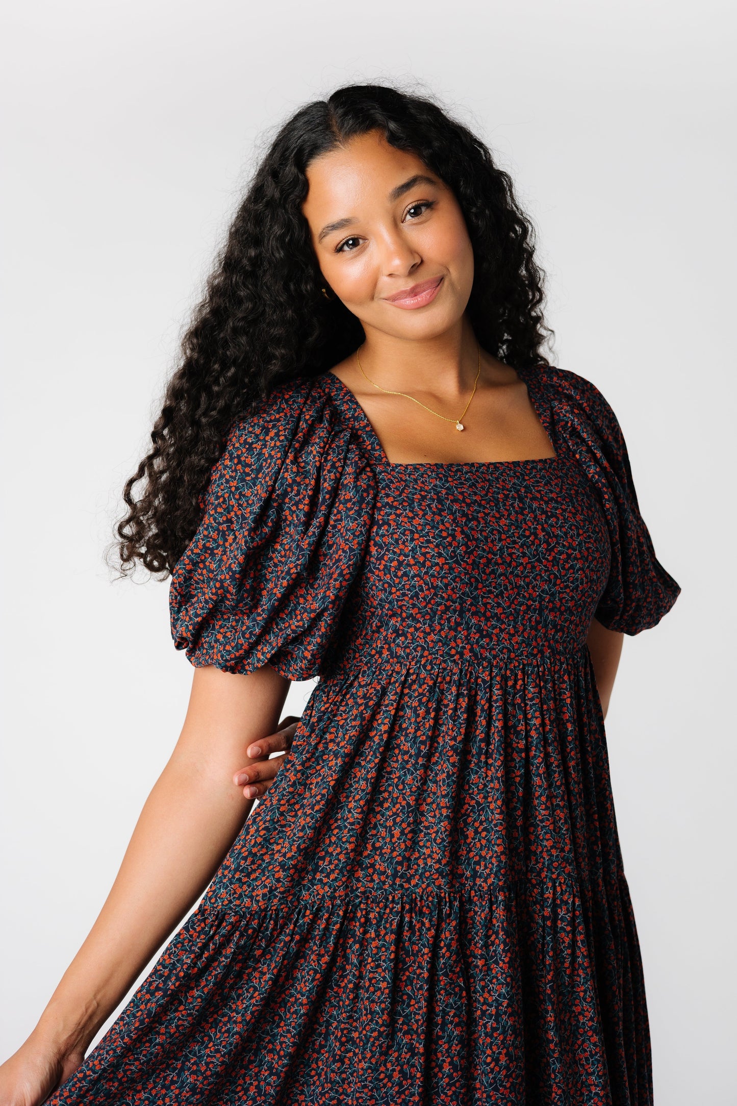 Close up view of black floral dress with square neckline, short puff sleeves and smocked bodice