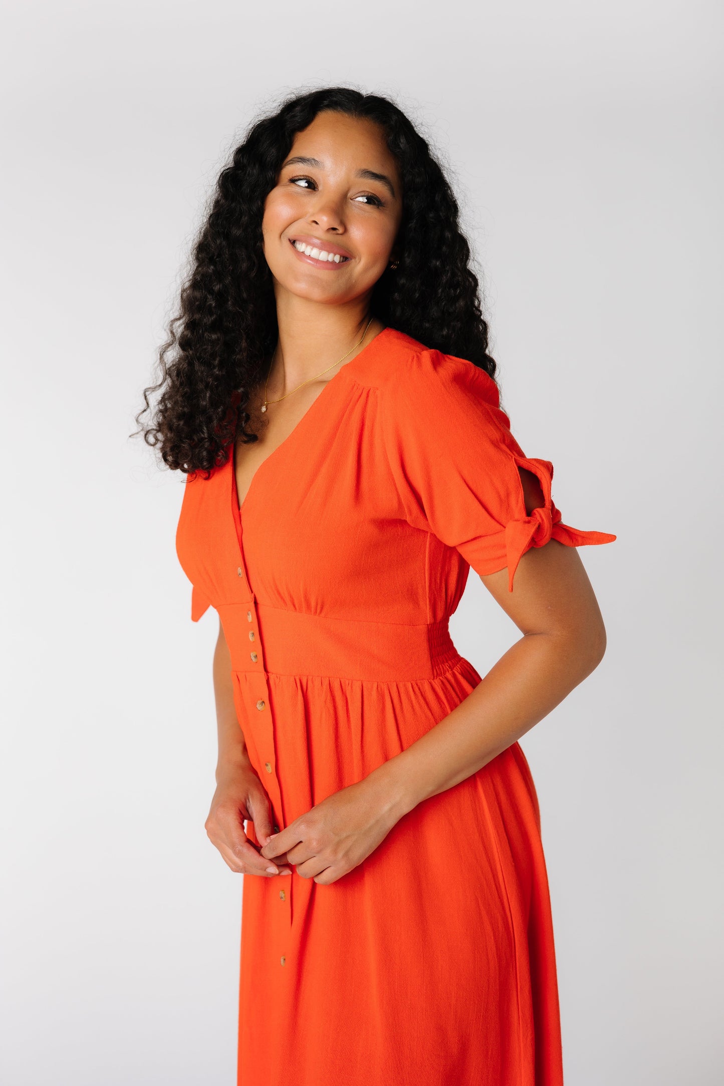 Close up side view of a red V-neck dress with wide waistband