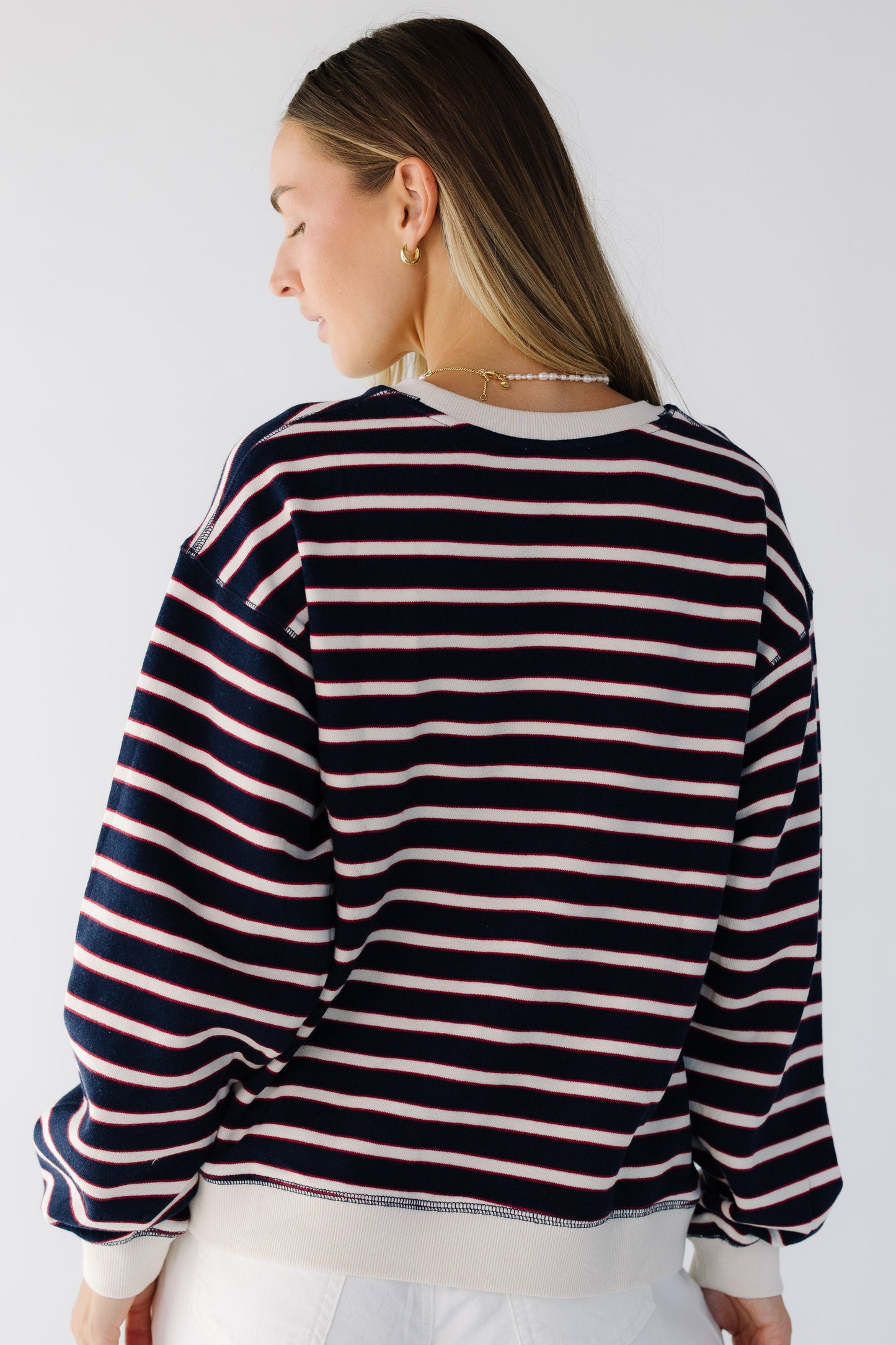 Back view of a woman wearing an over sized navy stripe top with long sleeves.