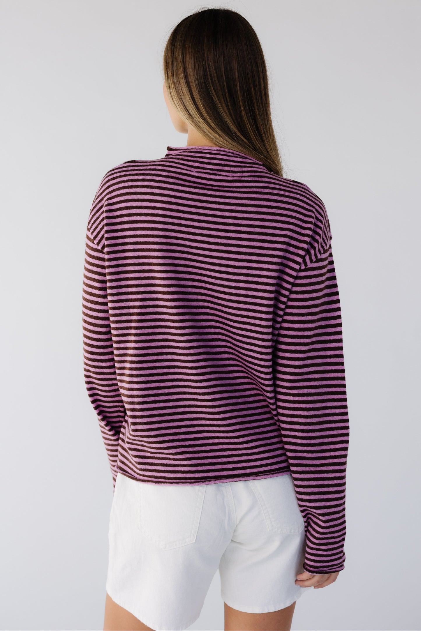 Back view of a woman wearing a pink & brown stripe long sleeve  lightweight sweater top.