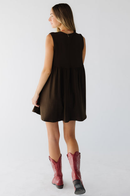 Back view of a young woman wearing a brown sleeveless mini dress.