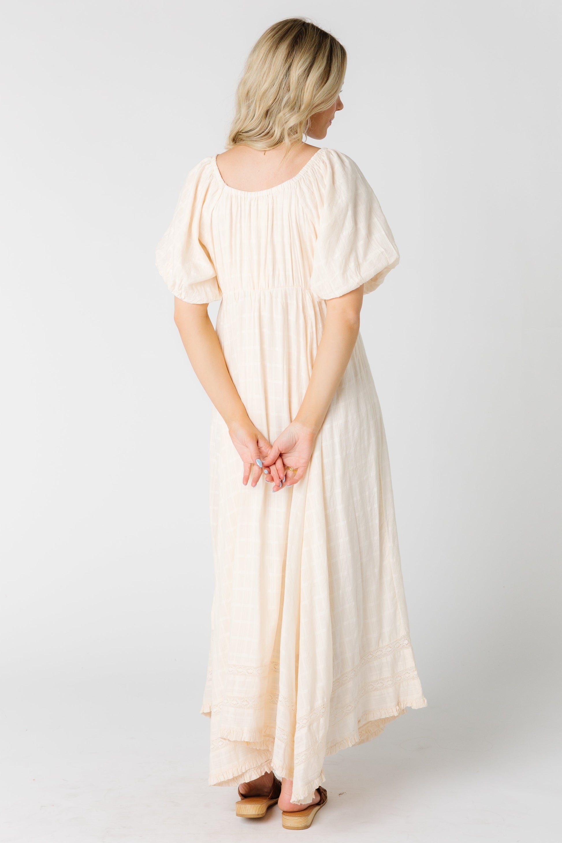 Back view of a woman wearing a cream maxi dress with short balloon sleeves