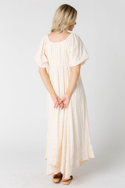 Back view of a woman wearing a cream maxi dress with short balloon sleeves