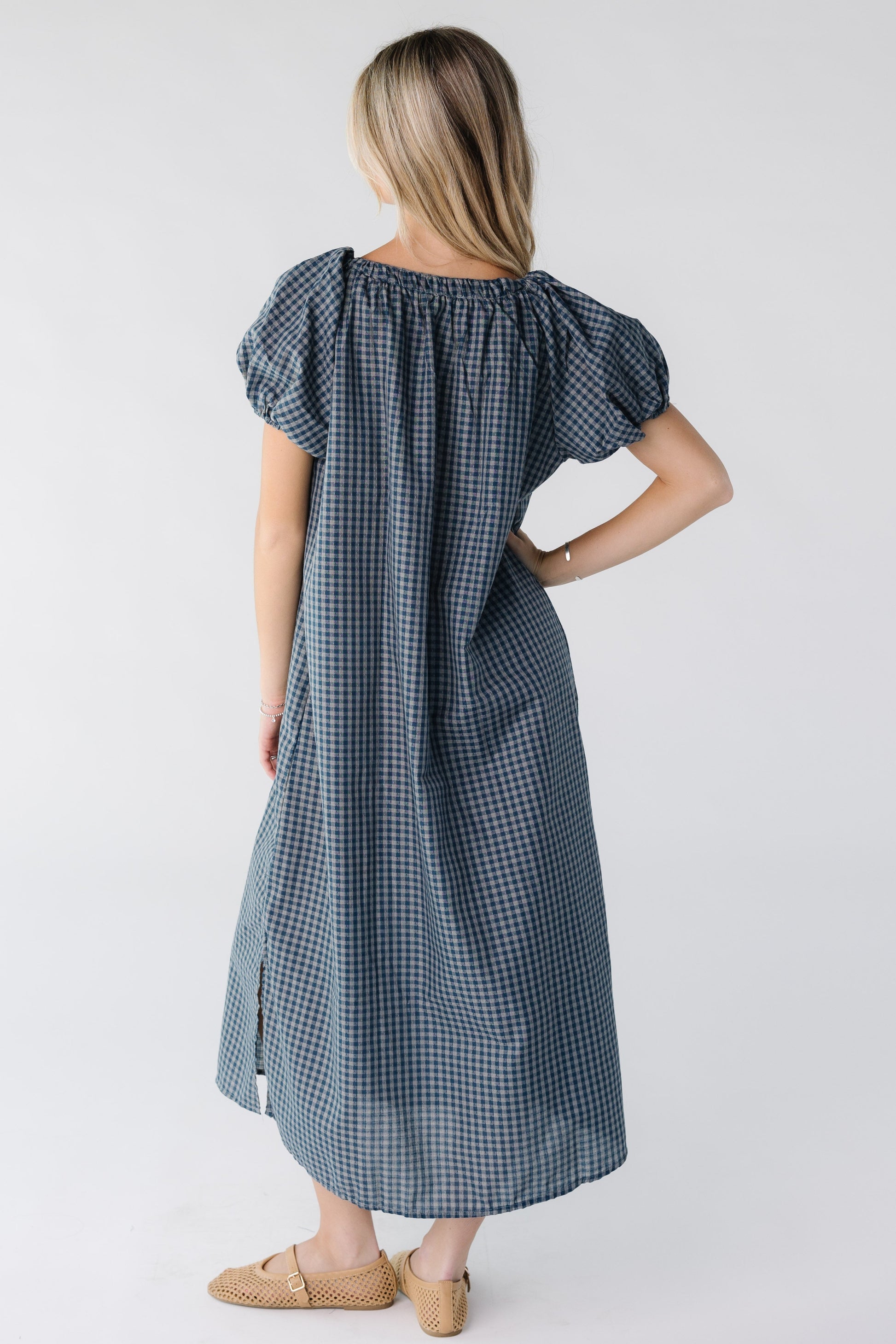 Back view of a woman wearing a blue gingham midi dress with short sleeves