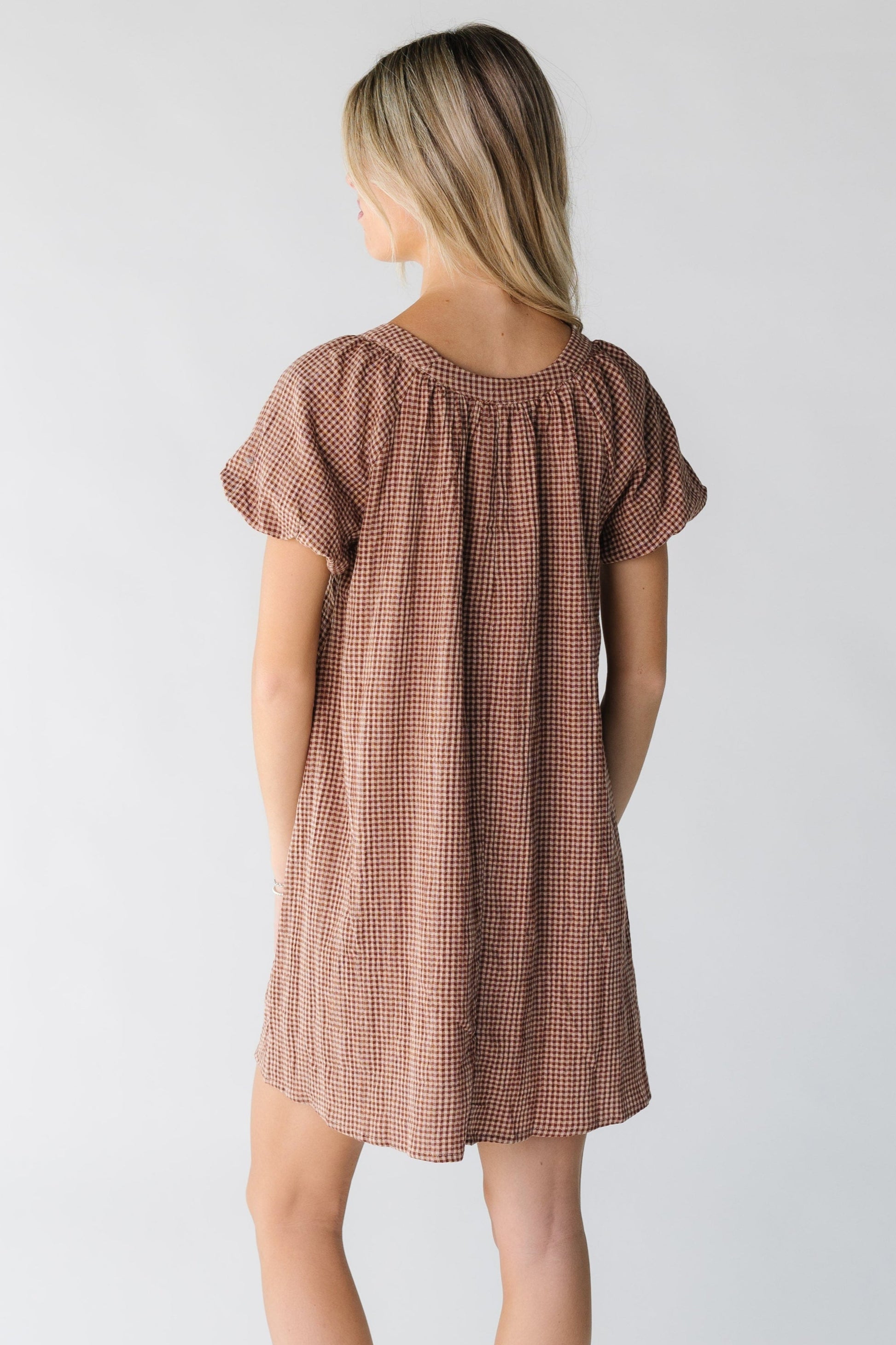 Back view of a woman wearing a brown gingham dress