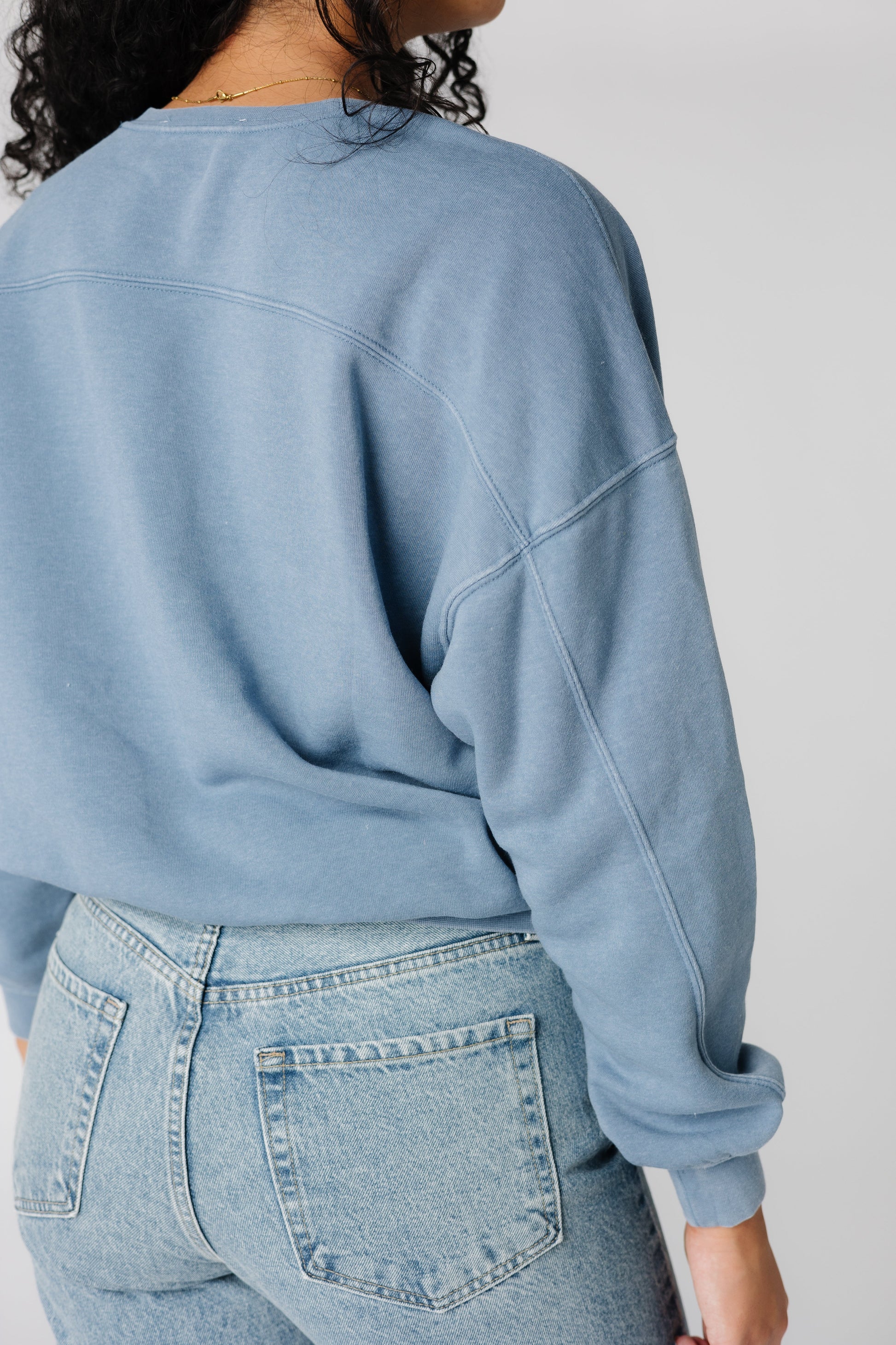 Close back view of blue sweatshirt with decorative seams