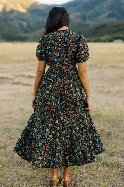 Back view of a woman wearing a slightly loose fitting midi-maxi dress with puff sleeves.