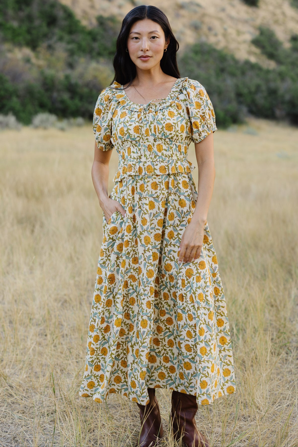 Young woman wearing a modest floral print midi dress with a ruffled scoop neckline, puff sleeves,wide waistband and a full skirt.