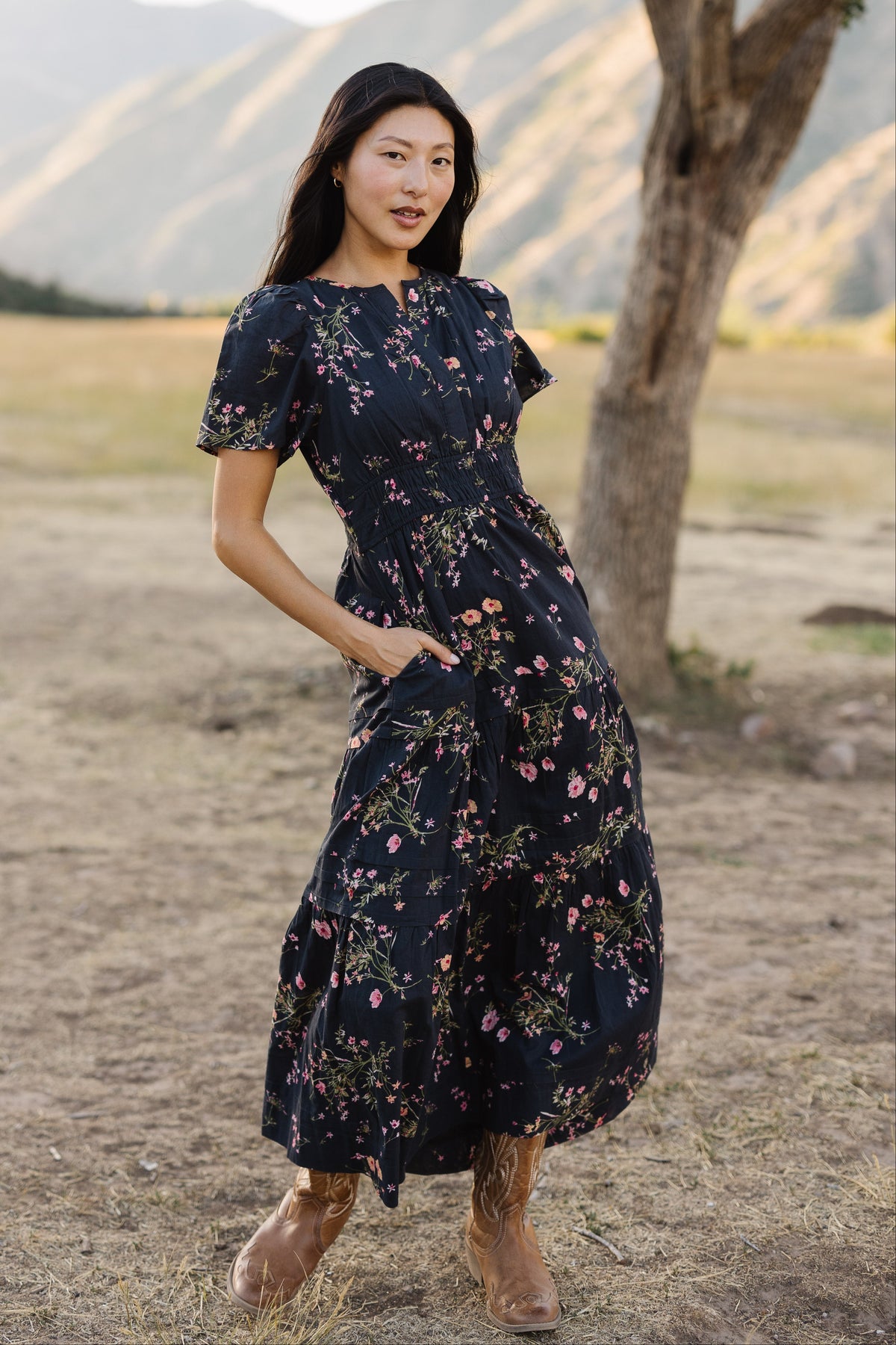 Young woman wearing a modest navy floral midi dress with a V-neckline, short sleeves, wide elastic waistband and side pockets.