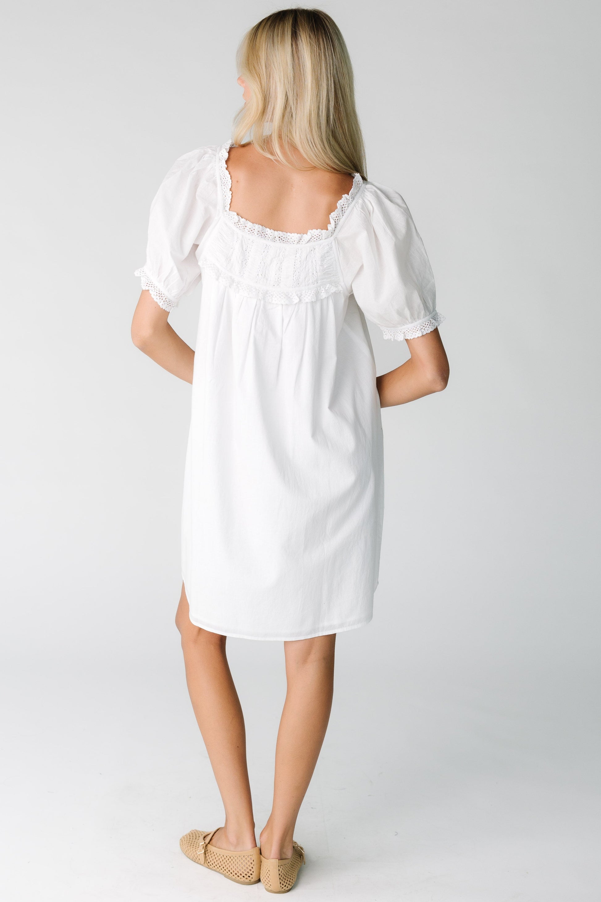 Back view of a woman wearing a white dress with square neckline with short sleeves