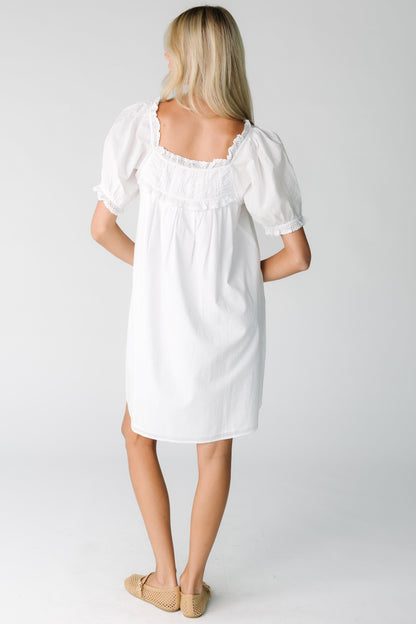 Back view of a woman wearing a white dress with square neckline with short sleeves