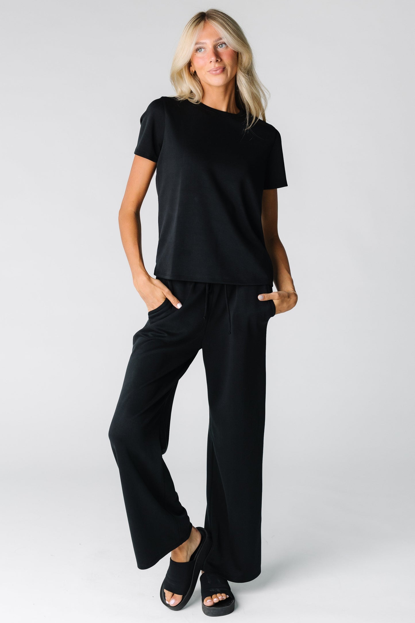 Woman wearing a 2 piece lounge set in black with short sleeves and full length pant
