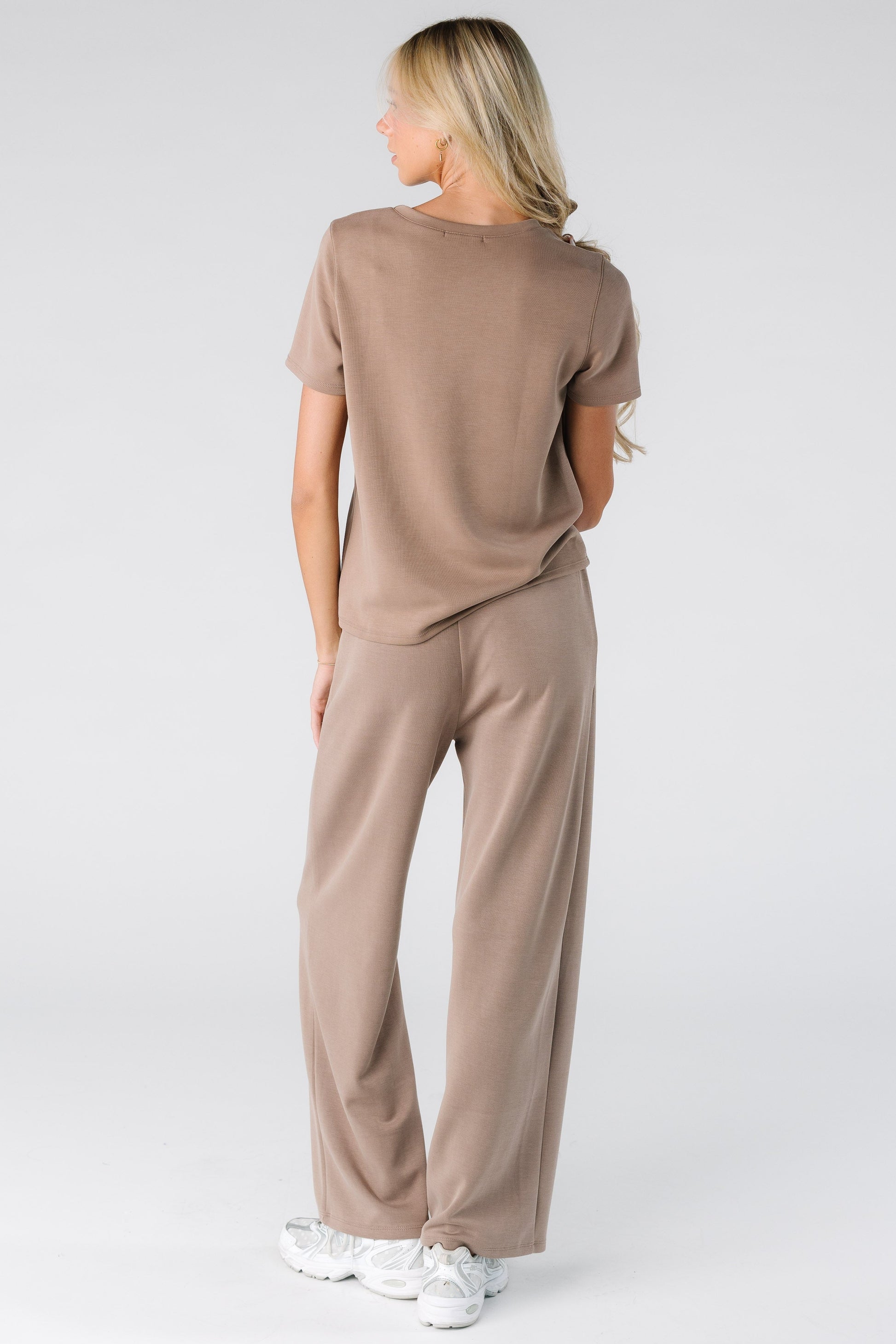 Back view of a woman wearing a 2 piece lounge set with short sleeves and full length pant in mocha