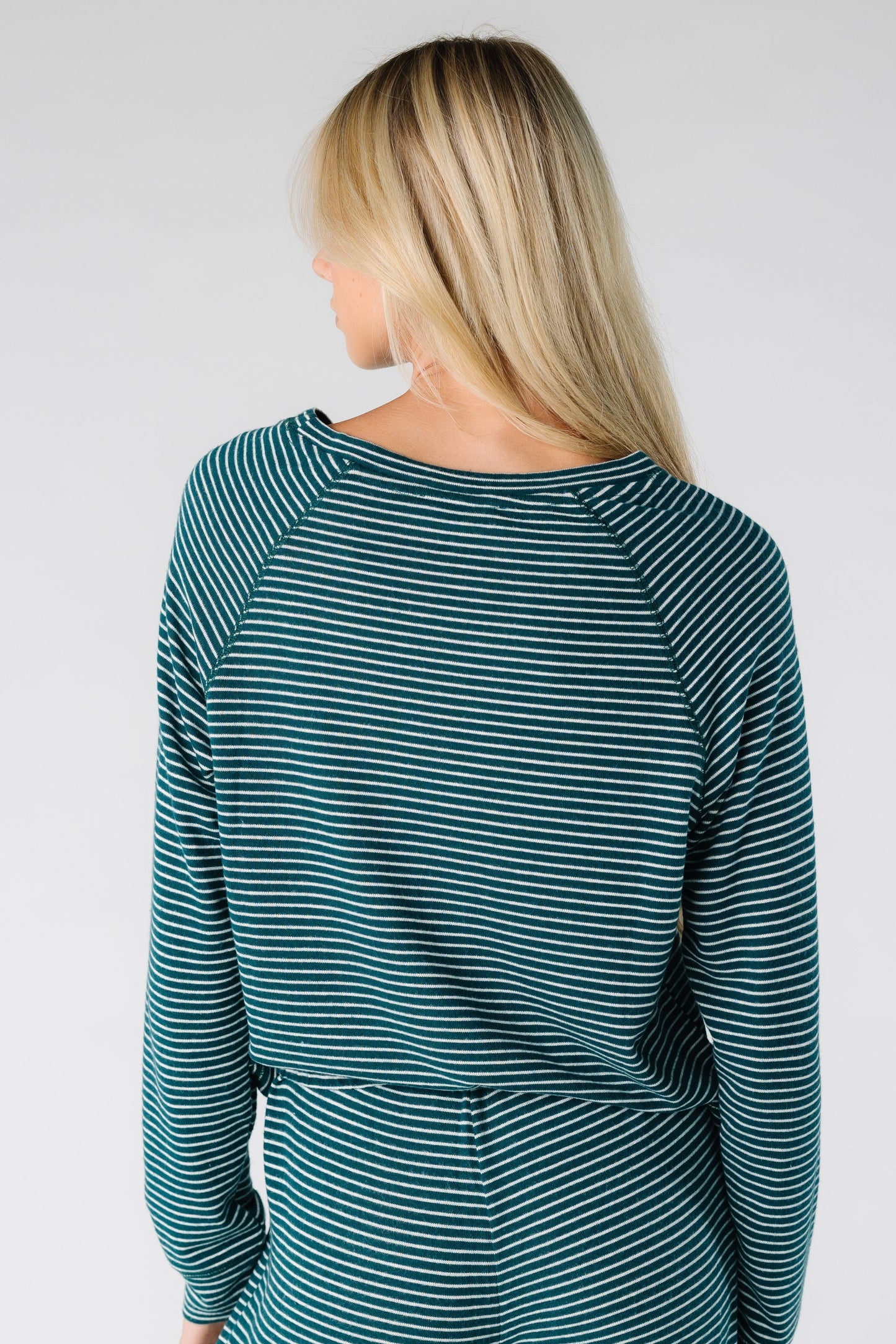 Back view of a women wearing a long sleeve soft top with round neckline