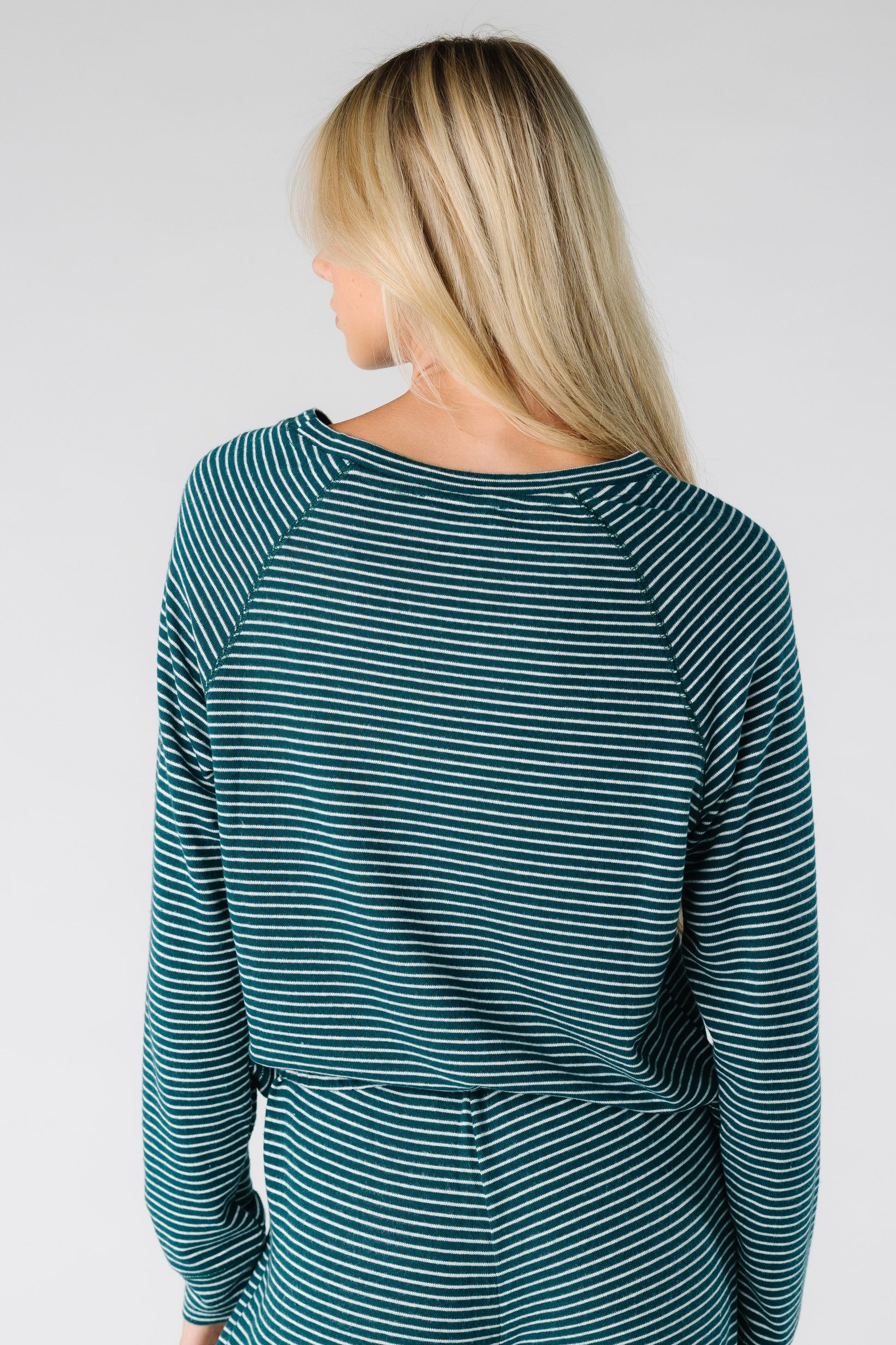 Back view of a women wearing a long sleeve soft top with round neckline