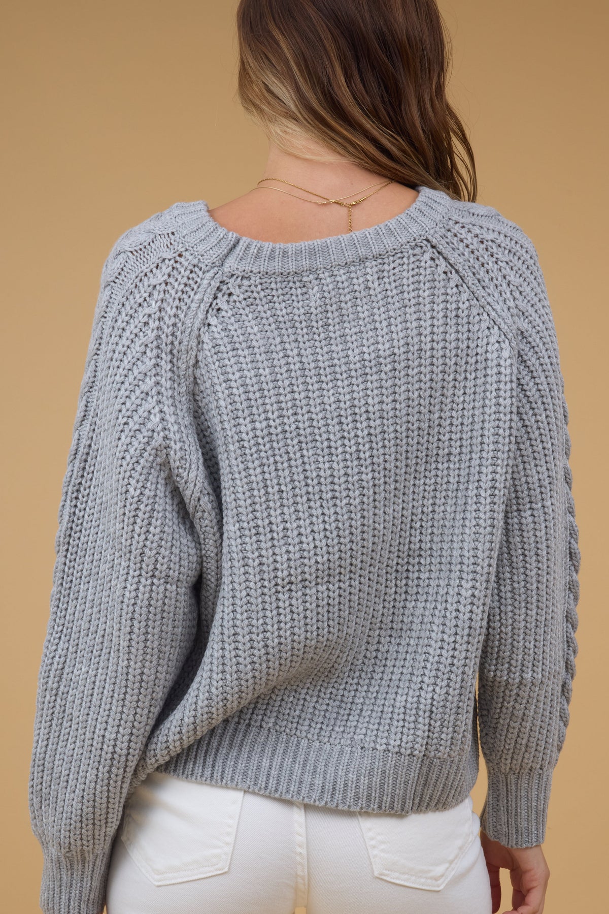 Back view of a woman wearing a grey loose fitting sweater.