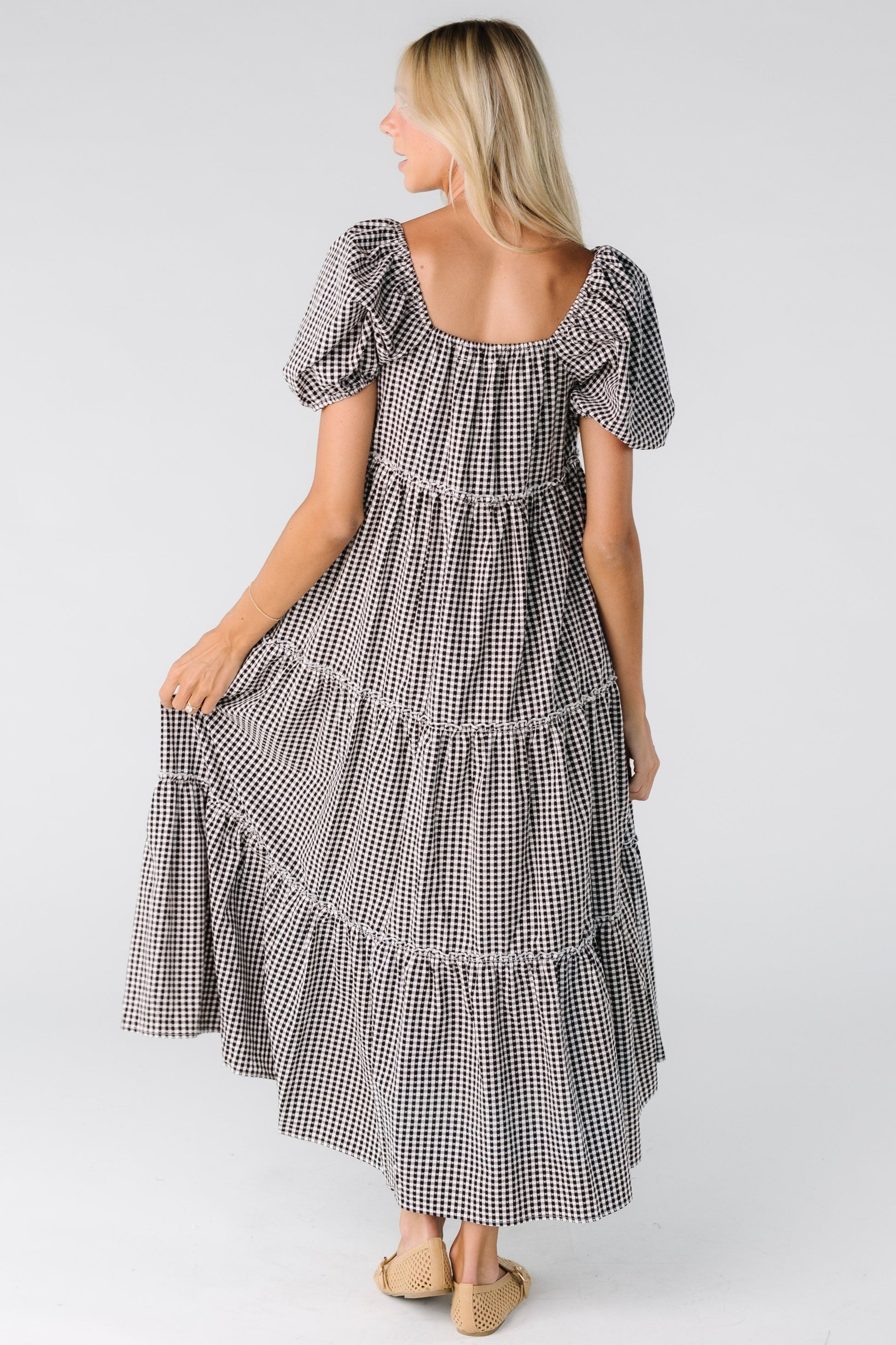 Back view of a woman wearing a black and white gingham midi