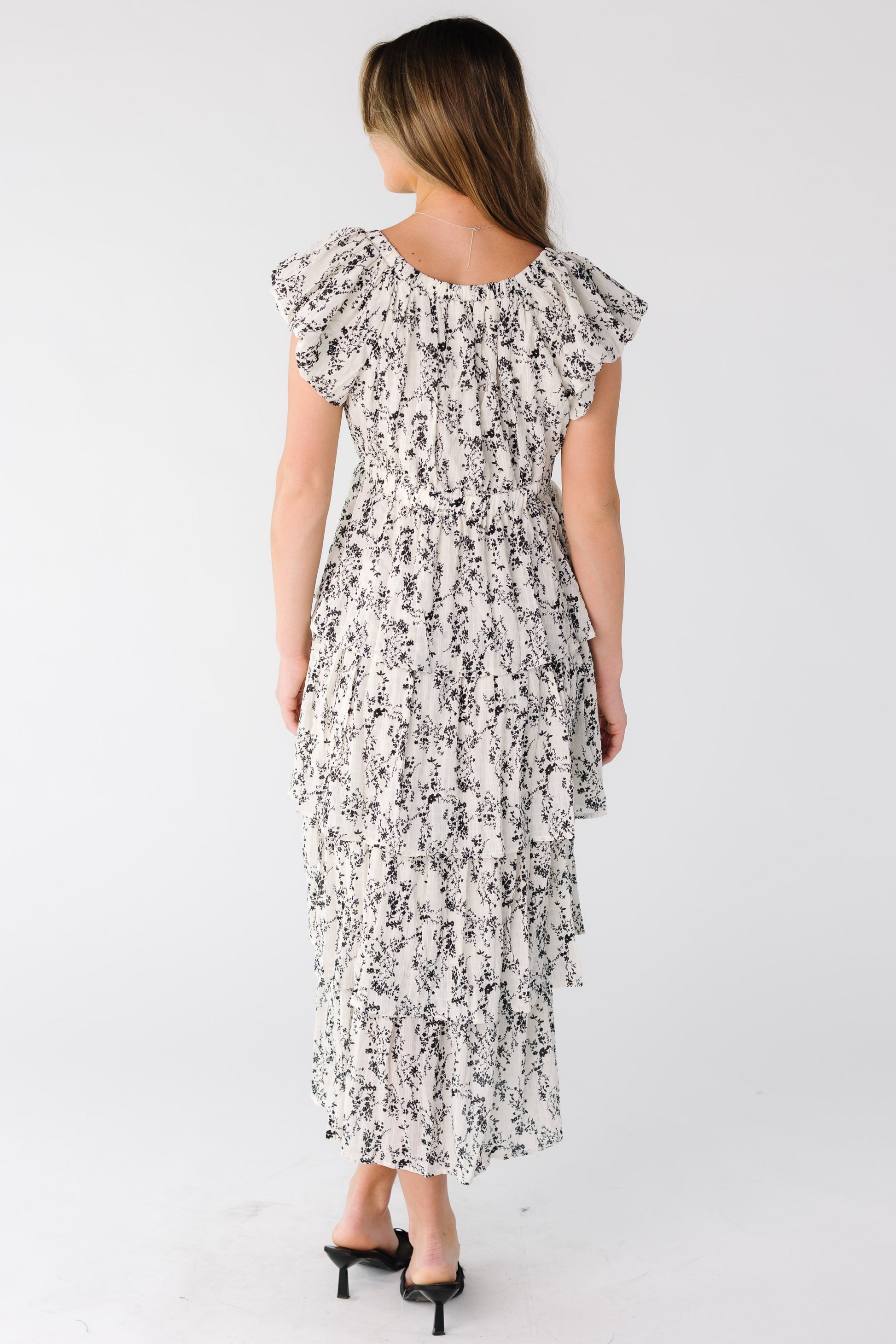 Back view of a woman wearing a white print tiered midi dress