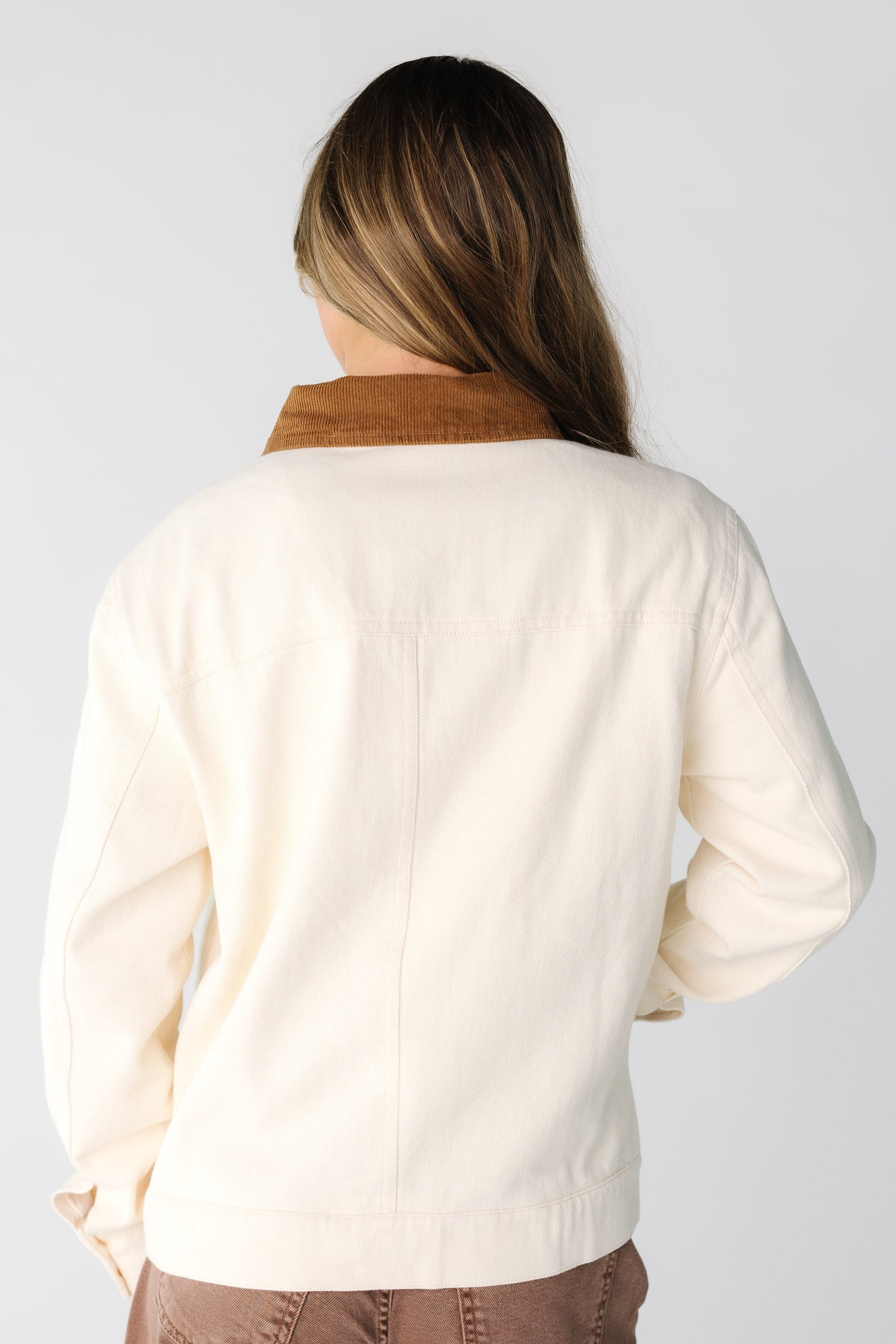 Back view of a woman wearing a cream jacket with brown collar