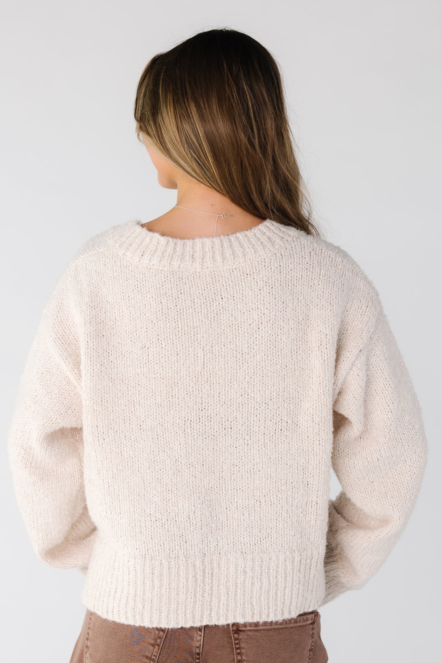 Back view of a woman wearing a cream loose fitting sweater