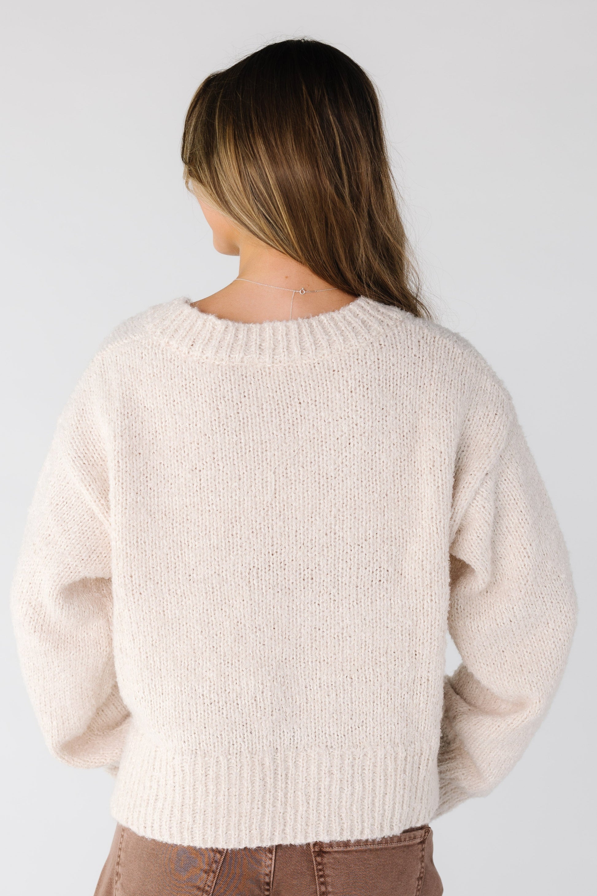 Back view of a woman wearing a cream loose fitting sweater