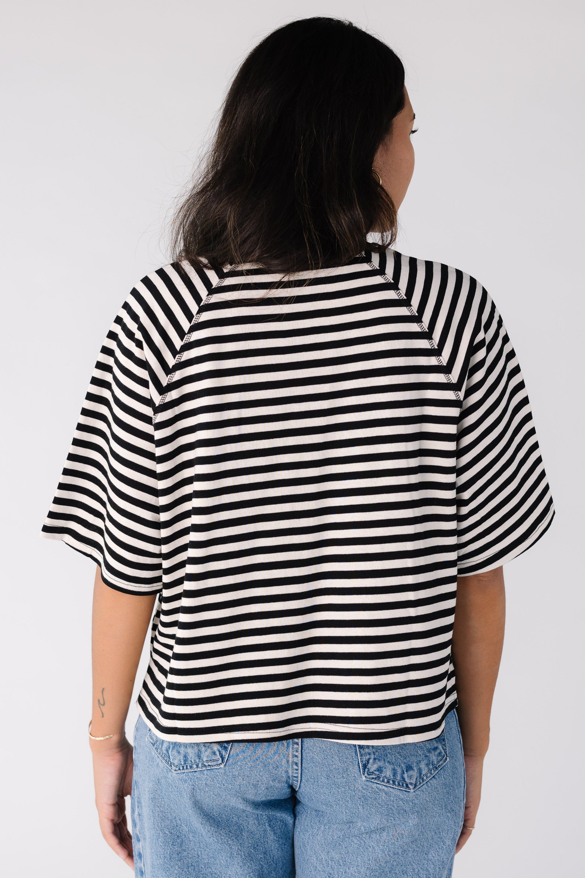Back view of a woman wearing a short sleeve black and white tee with interesting seam details