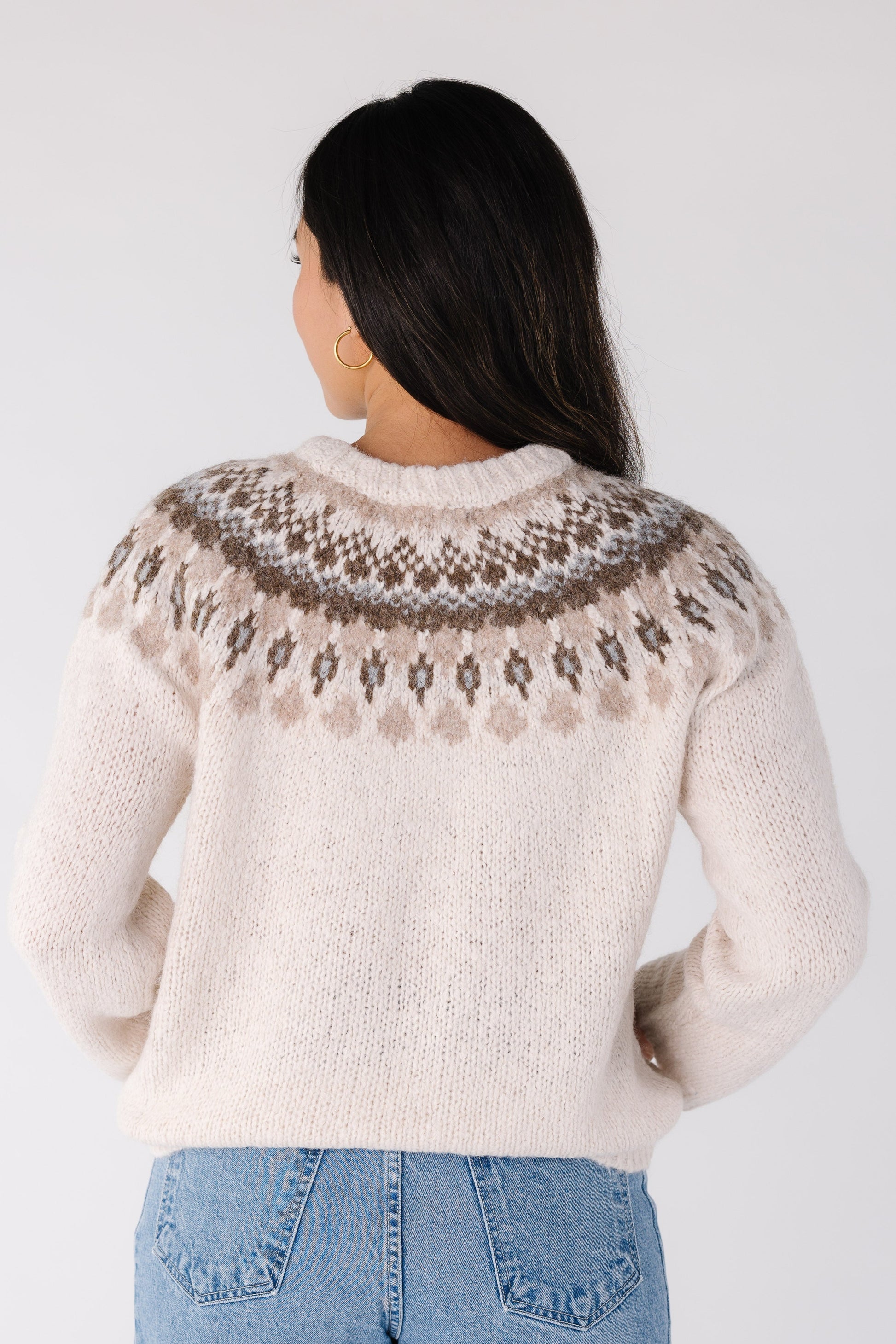 Back view of a woman wearing an ivory sweater with long sleeves