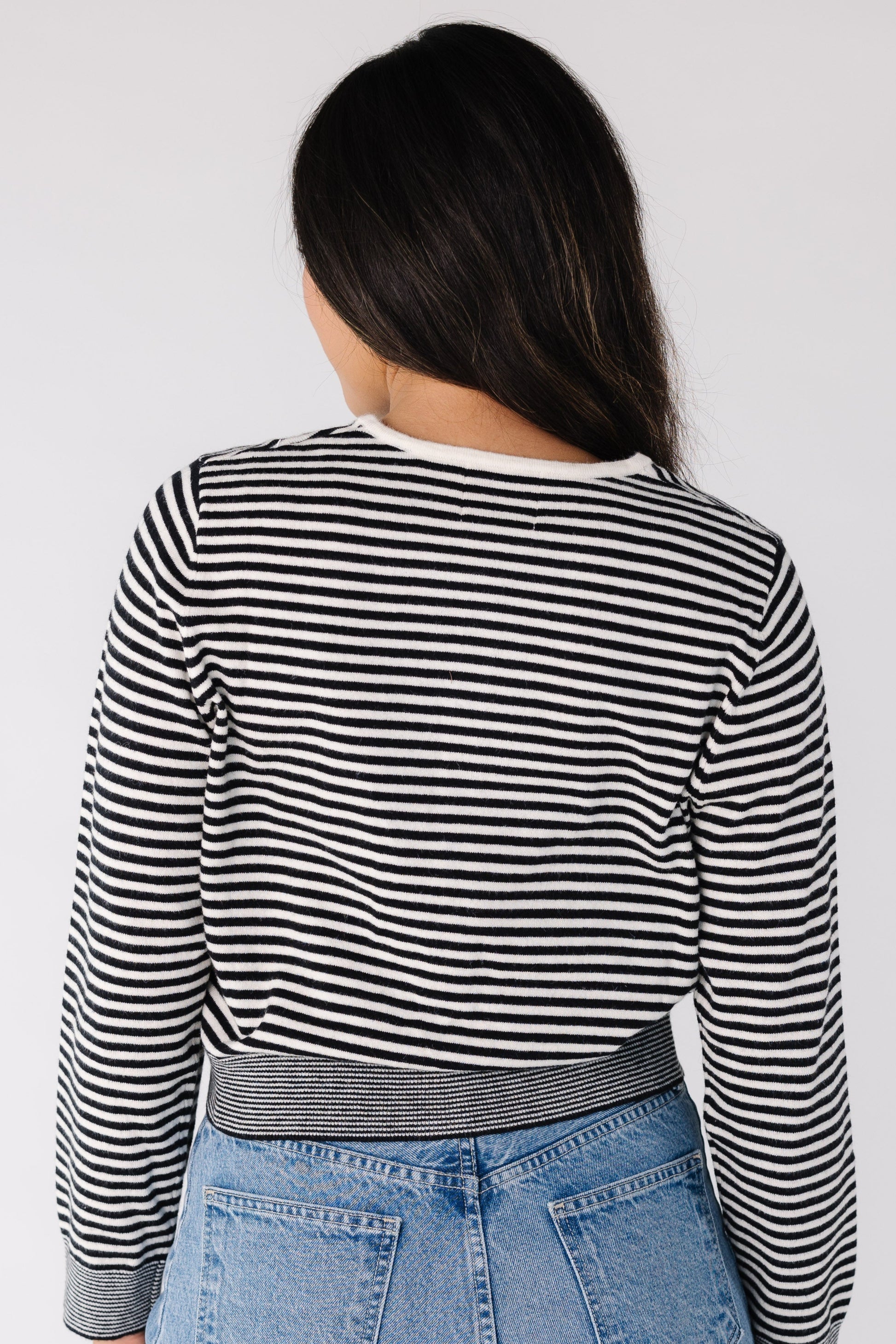 Back view of a woman wearing a black and white stripe cardigan with long sleeves