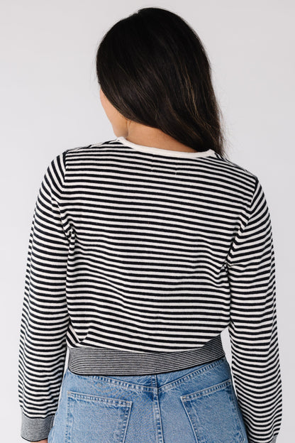 Back view of a woman wearing a black and white stripe cardigan with long sleeves