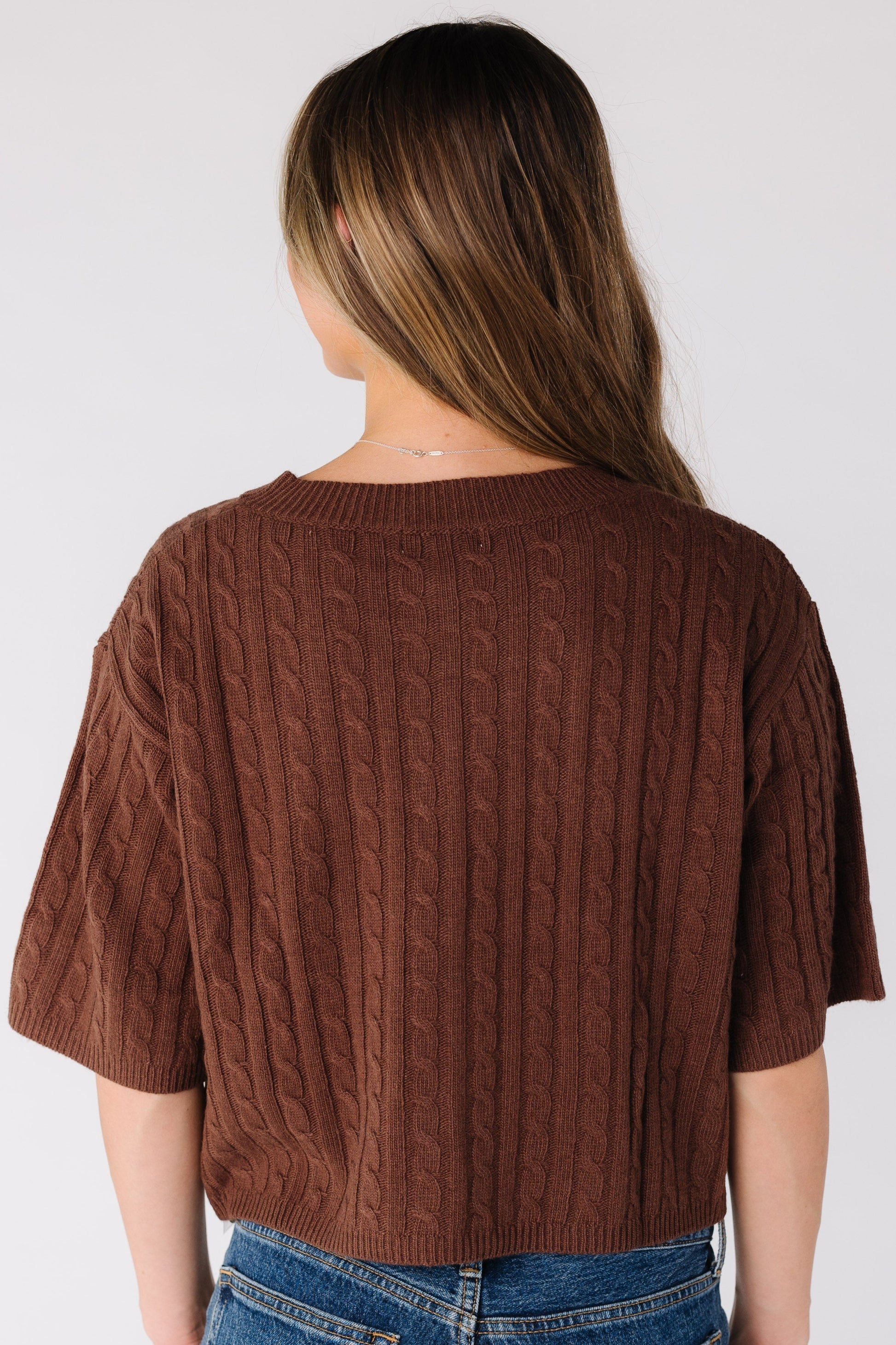 Back view of a woman wearing a brown cable knit cardigan