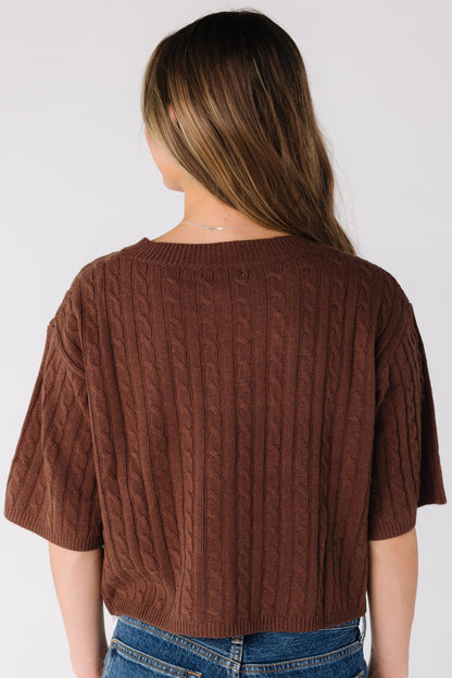 Back view of a woman wearing a brown cable knit cardigan