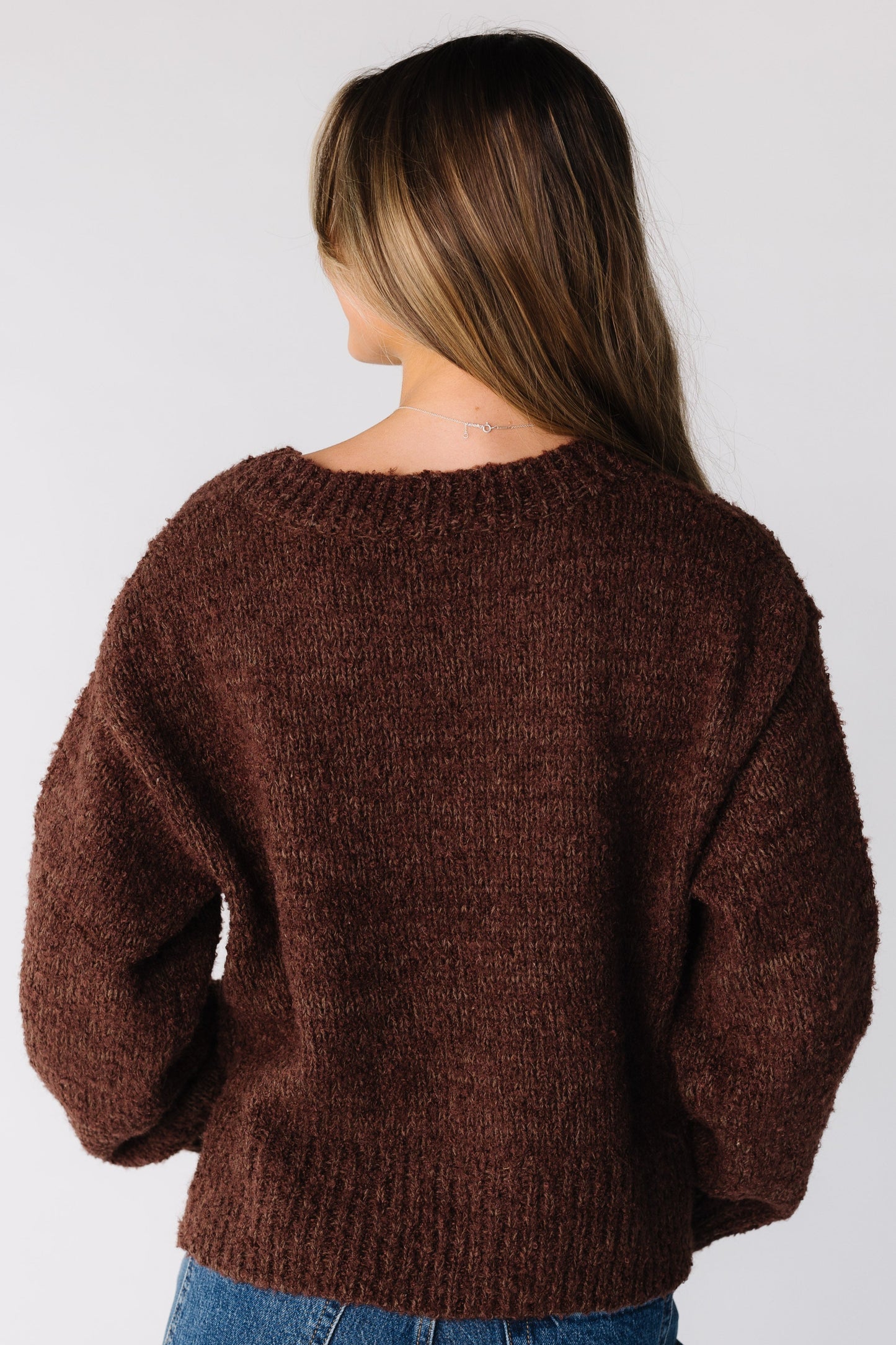 Back view of a woman wearing a brown loose fitting sweater