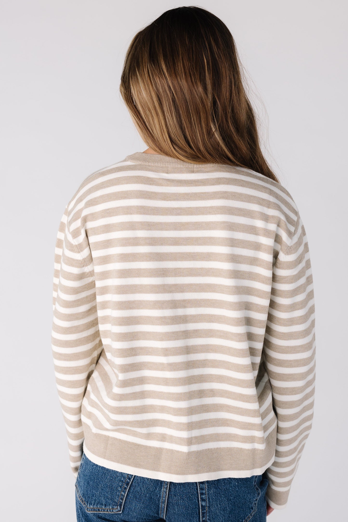 Back view of a woman wearing a beige stripe sweater