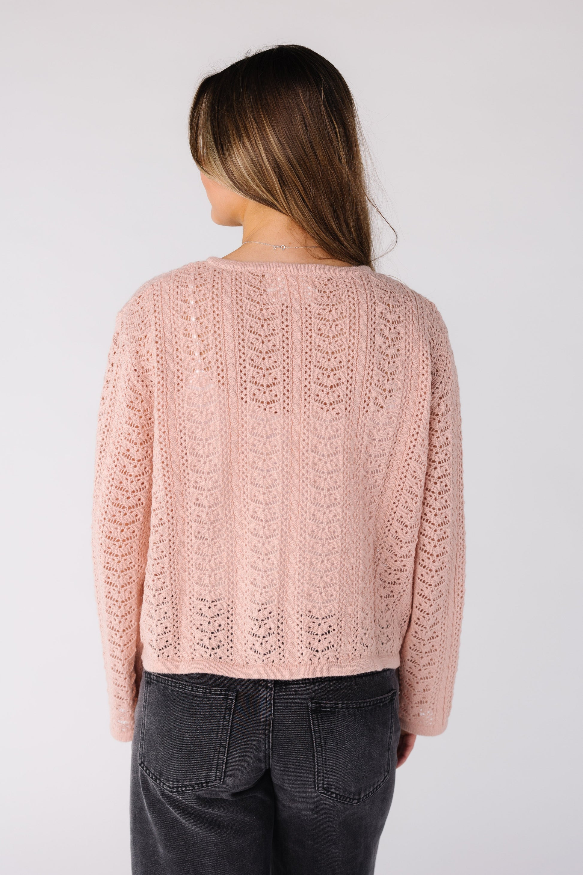 Back view of a woman wearing a pink lace cardigan