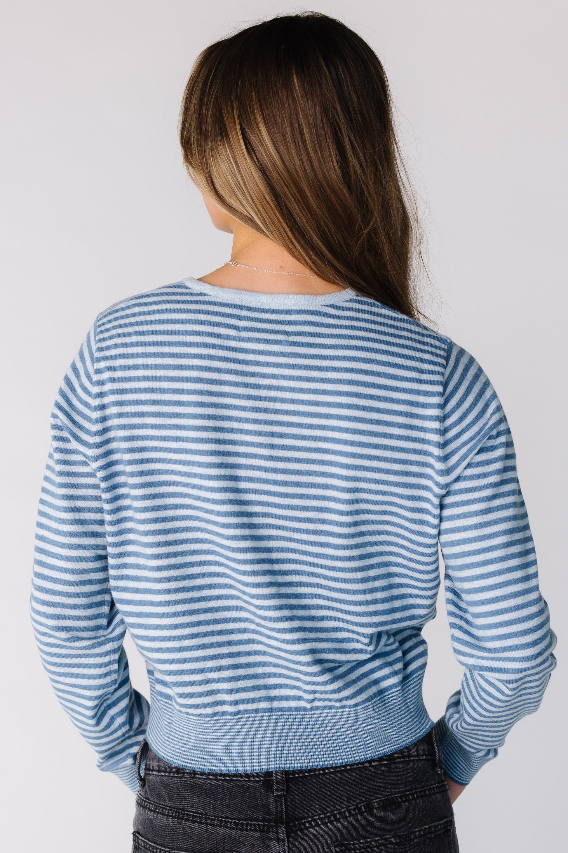 Back view of a woman wearing a blue stripe cardigan with long sleeves
