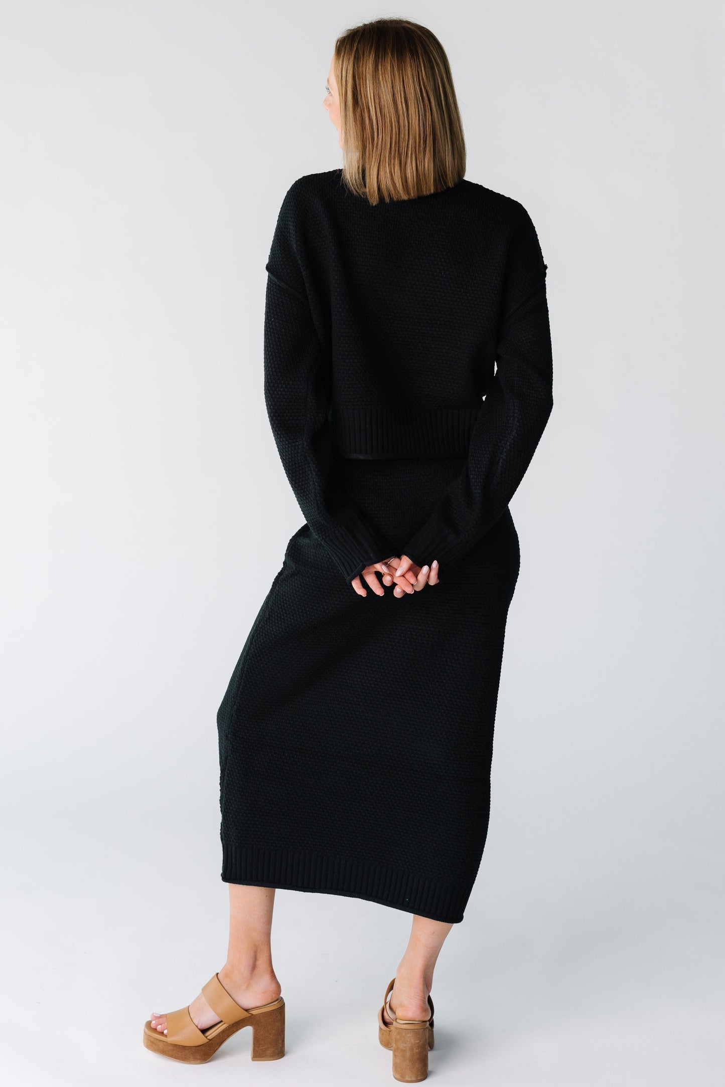 Back view of a woman wearing a black sweater and skirt set