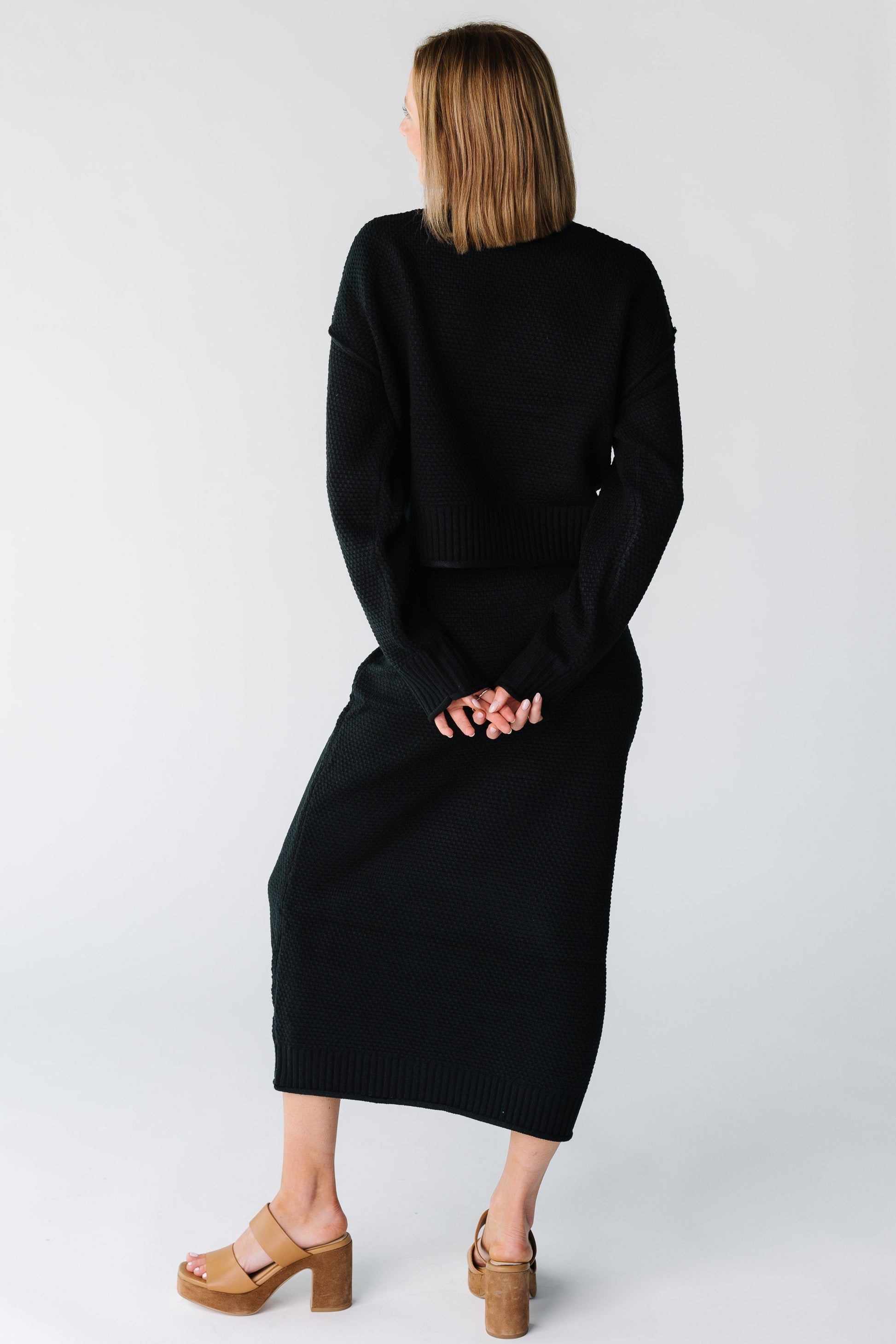 Back view of a woman wearing a black sweater and skirt set