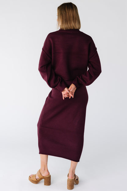 Back view of a woman wearing a dark burgundy sweater and midi skirt set