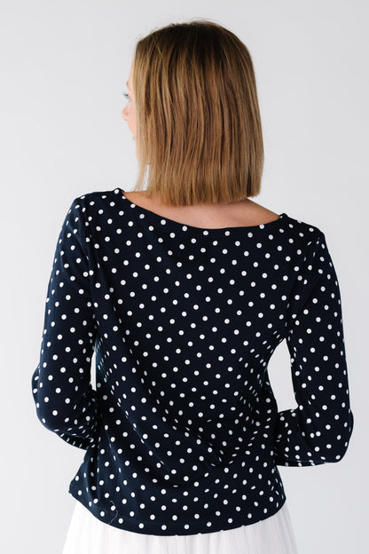 Back view of a woman wearing a navy polka dot top with wider neckline