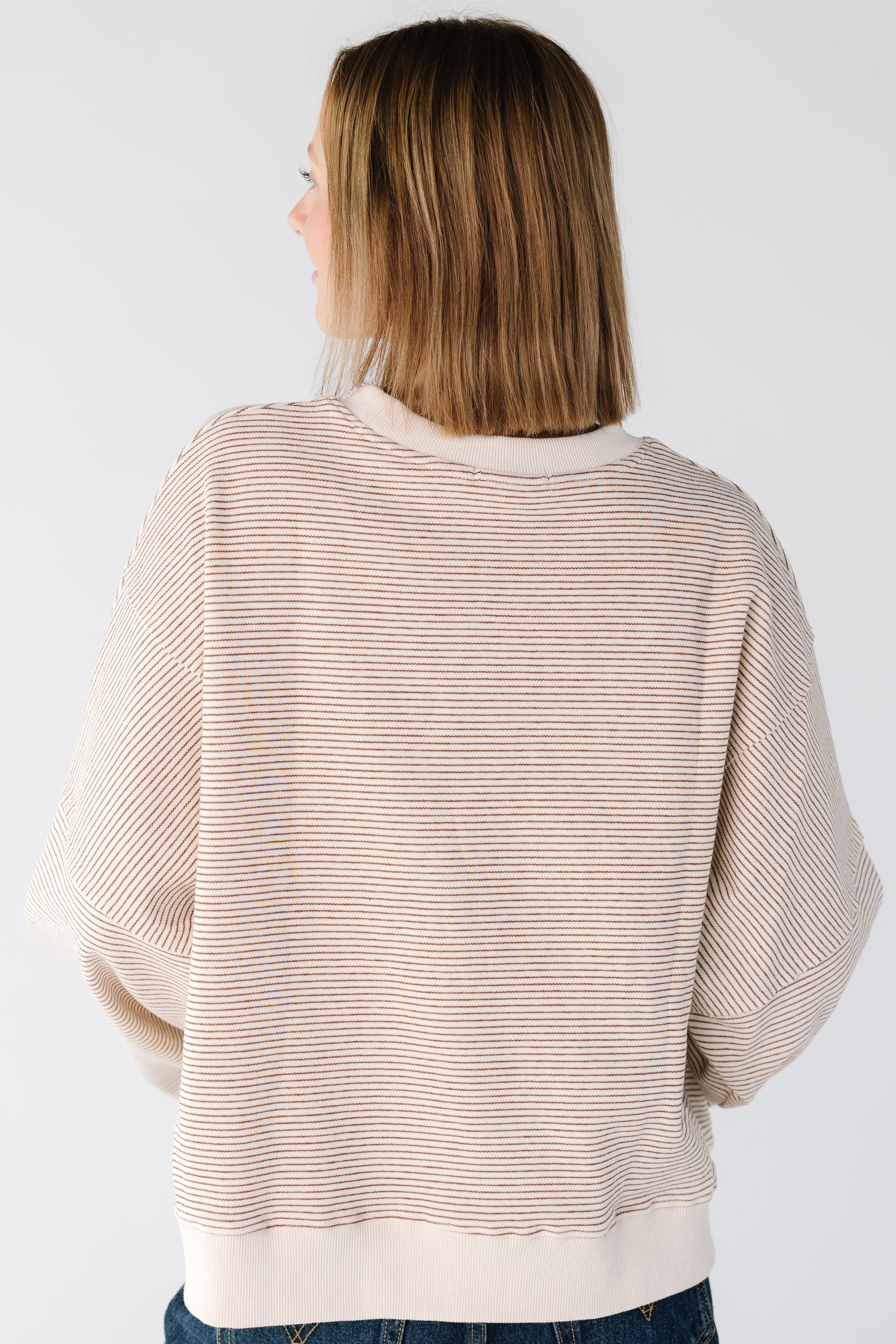 Back view of a woman wearing a camel stripe sweatshirt