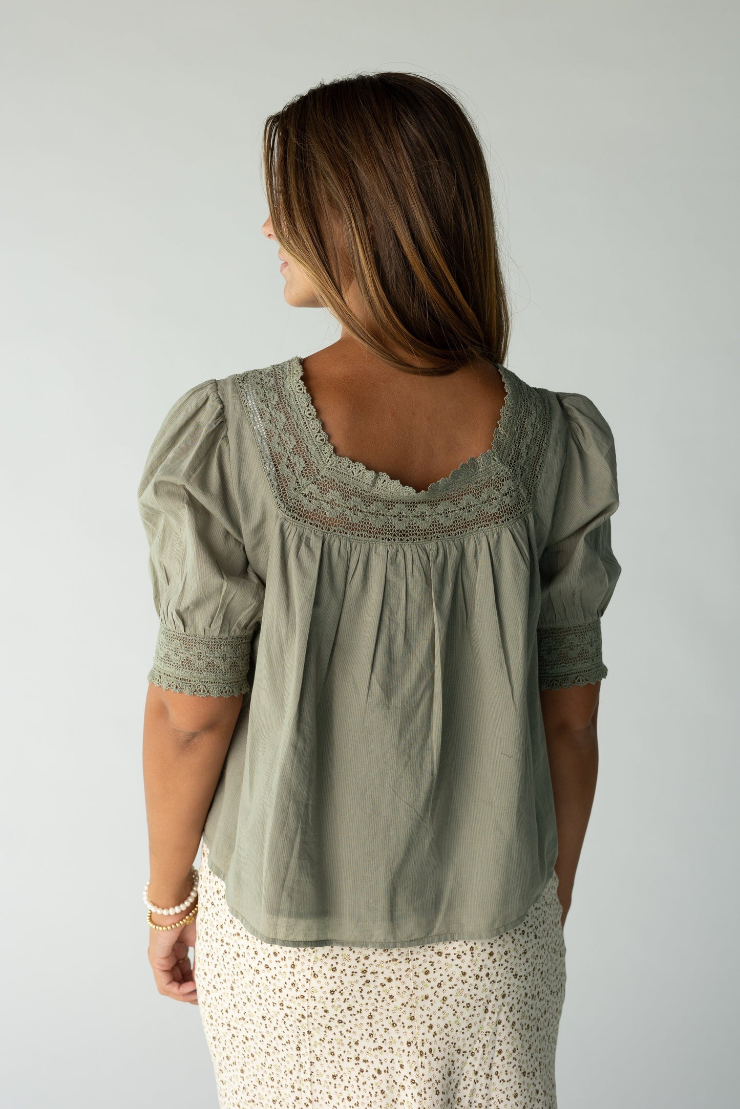Back view of an olive blouse with lace neckline with lace cuffs