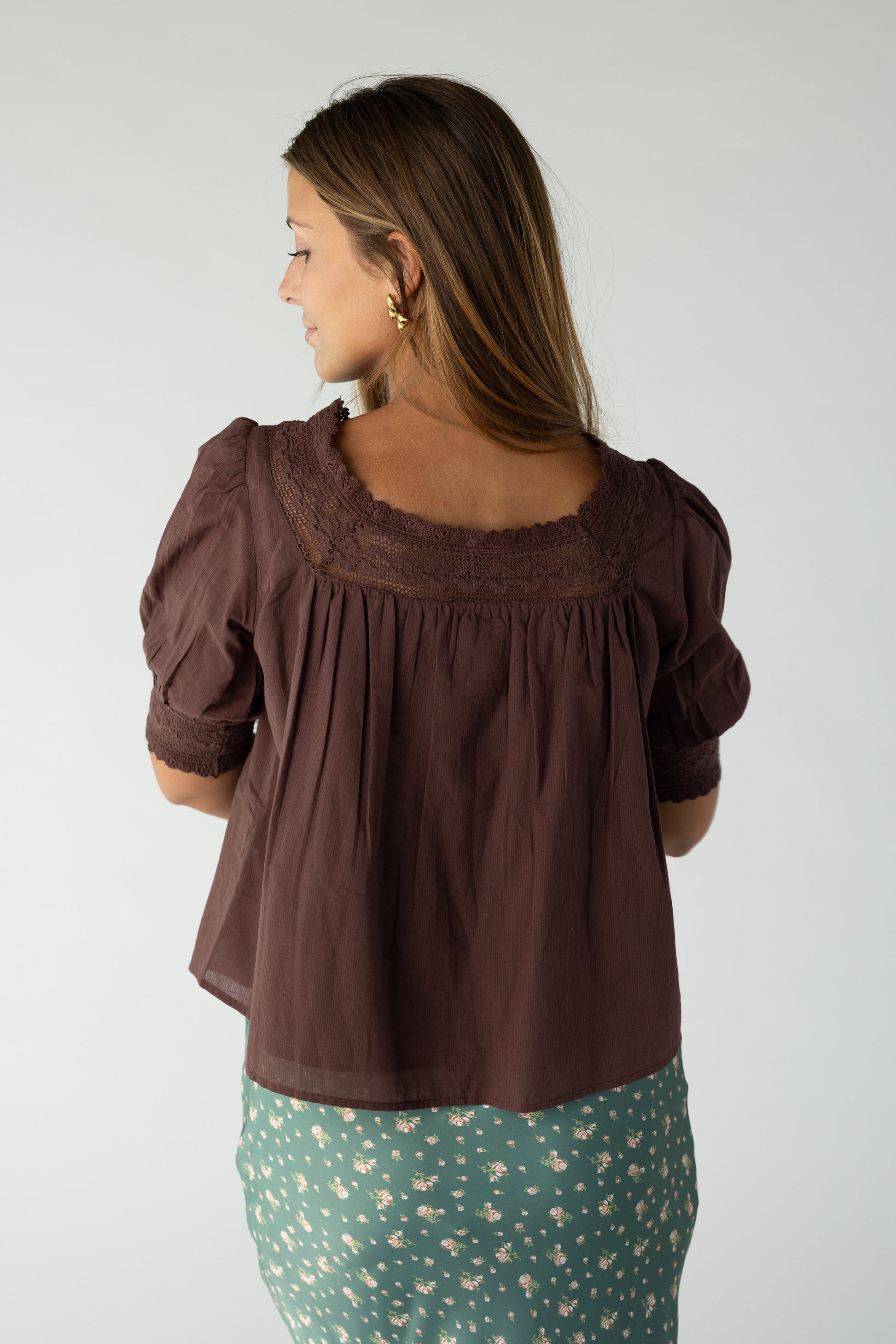 Back view of a woman wearing a brown bouse with lace neckline