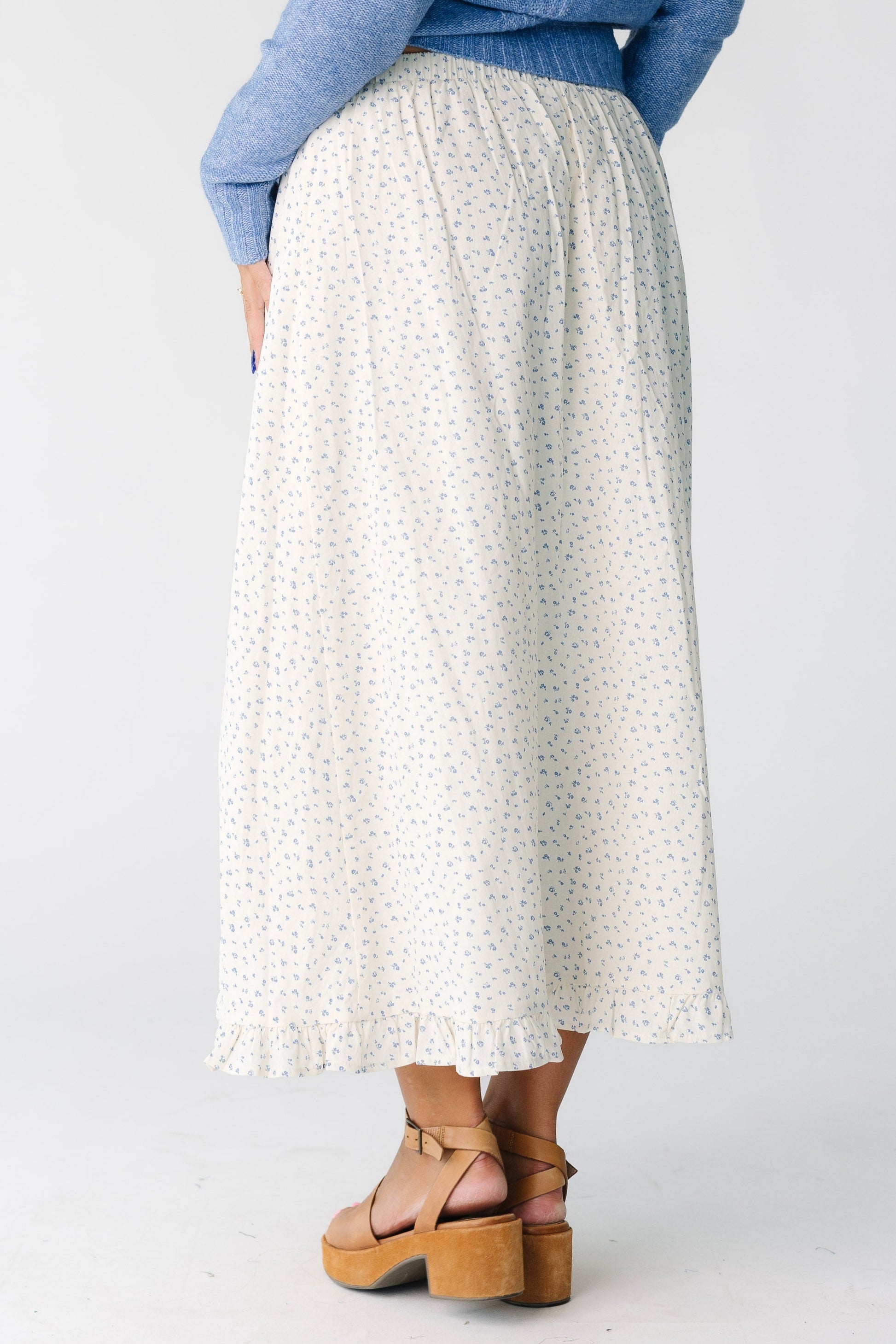 Back view of a woman wearing a  cream midi with ruffle hem