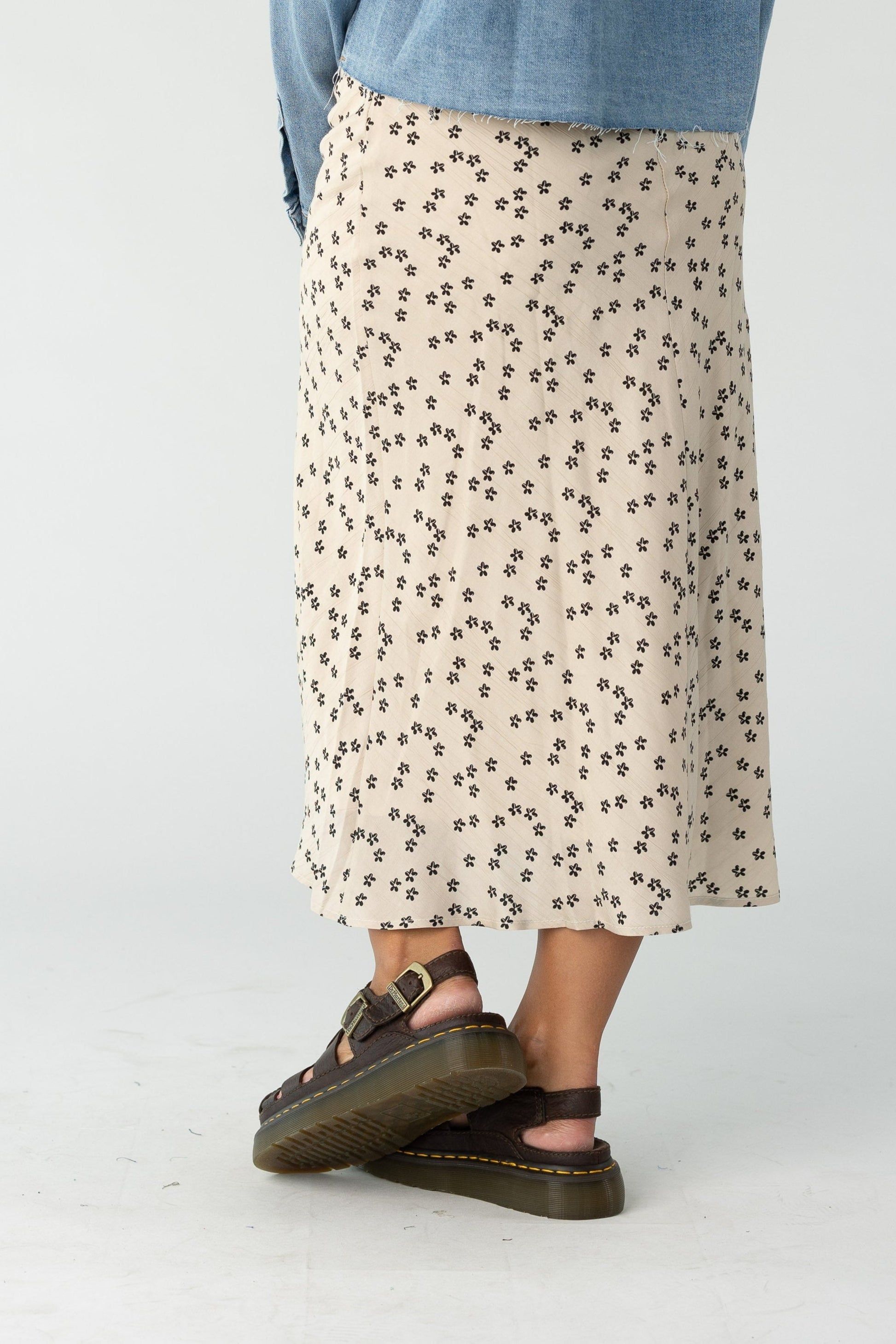 Back view of a woman wearing a tan midi skirt with black print
