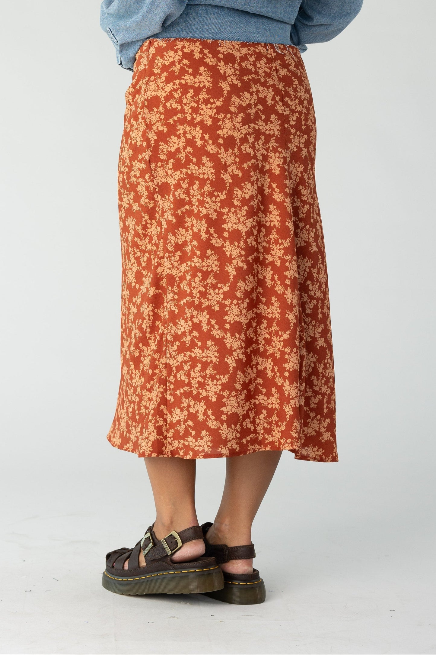 Back view of a woman wearing a rust floral print midi skirt