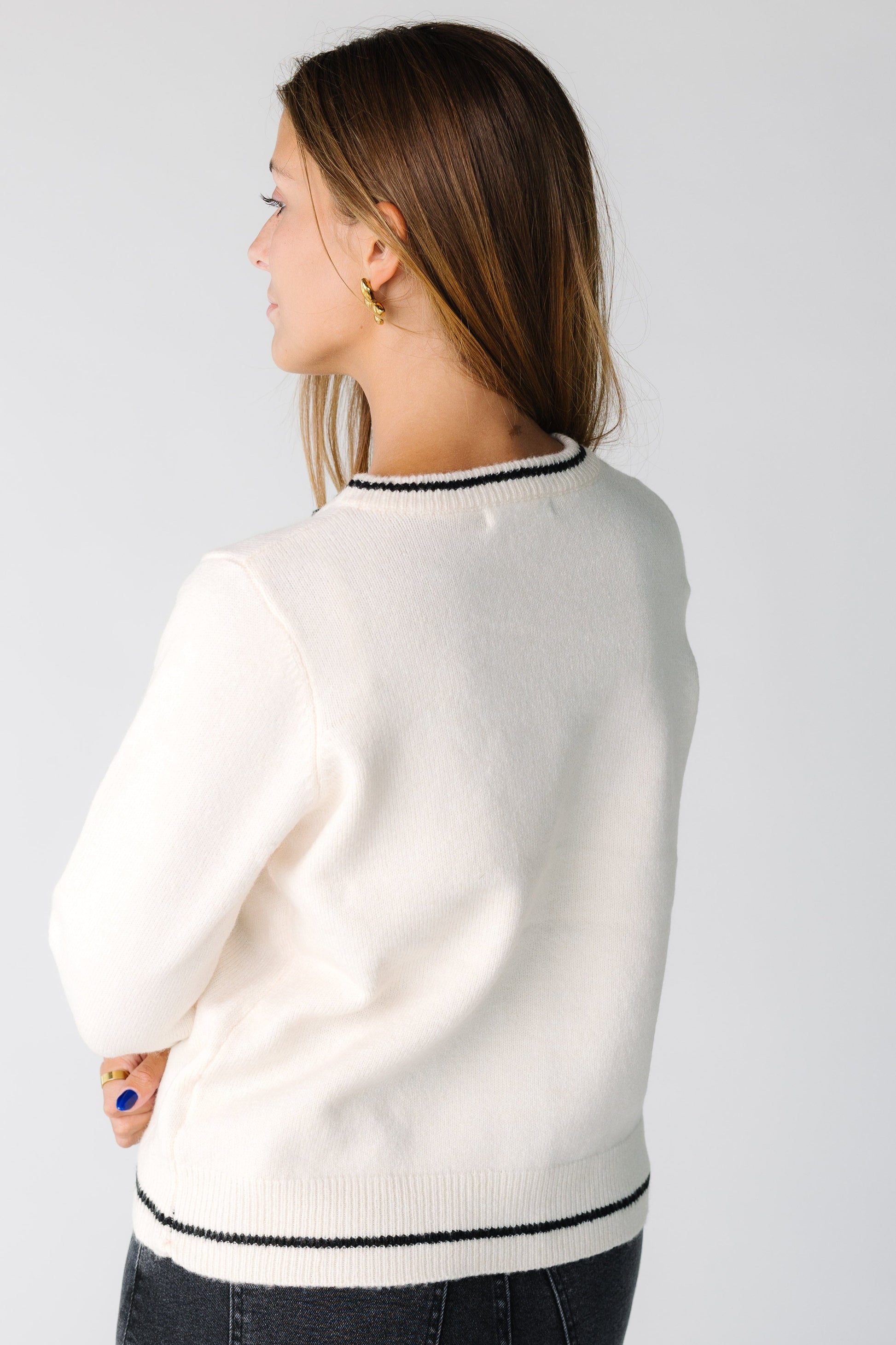 Back view of a woman wearing an ivory cardigan with a single black stripe