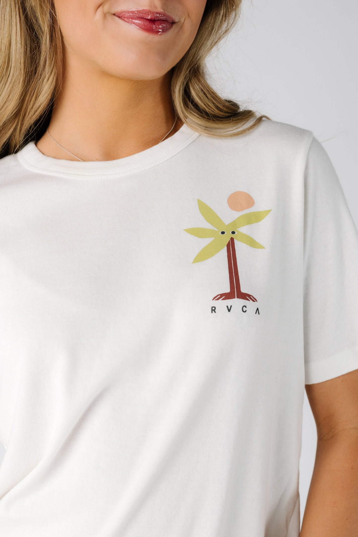 Close view of a woman wearing a white graphic tee with a small front graphic.