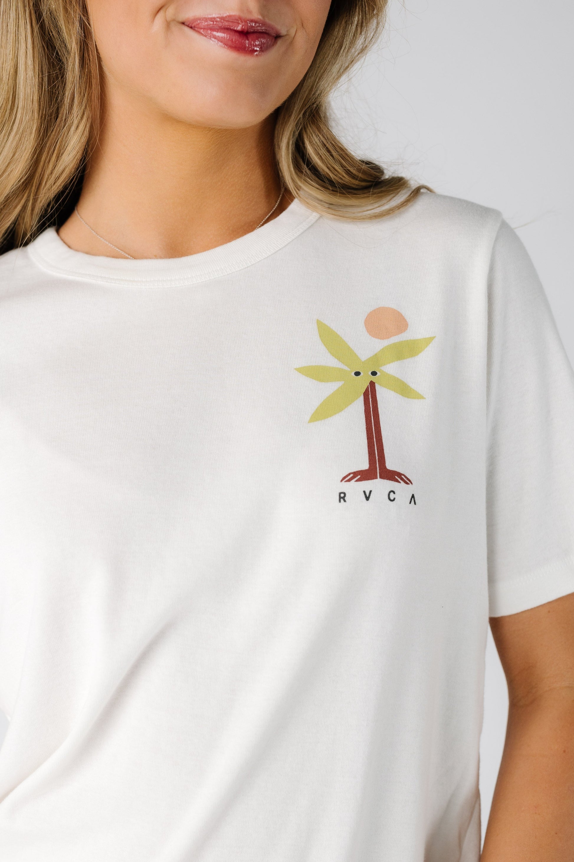 Close view of a woman wearing a white graphic tee with a small front graphic.
