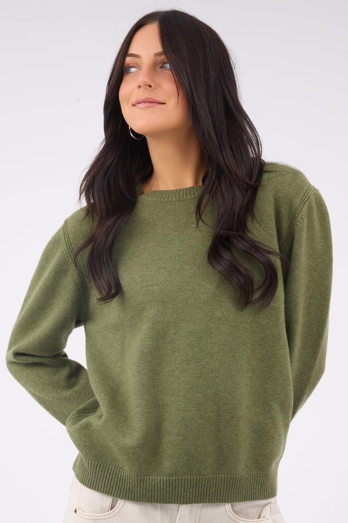A woman wearing an olive crew neck sweater with long sleeves.