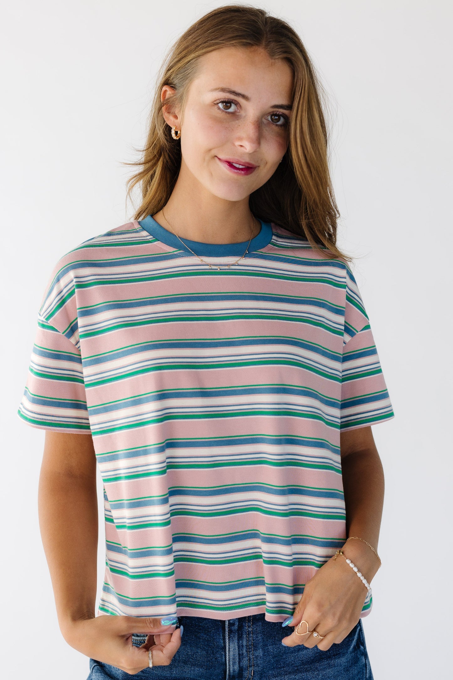 Young woman wearing a modest short sleeve tee with a crew neckline in a pink and multicolor stripe.